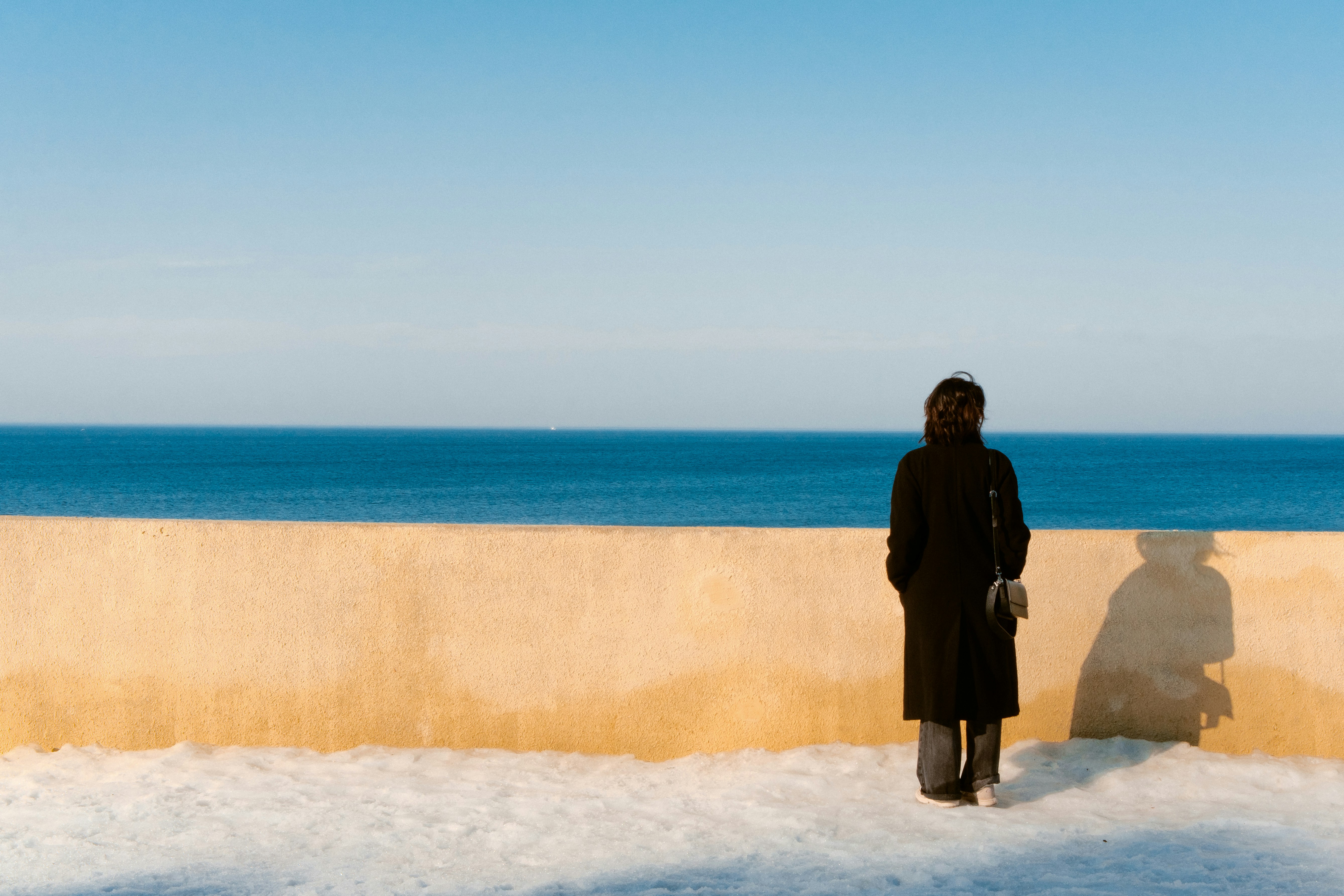 Woman in coat standing by the ocean