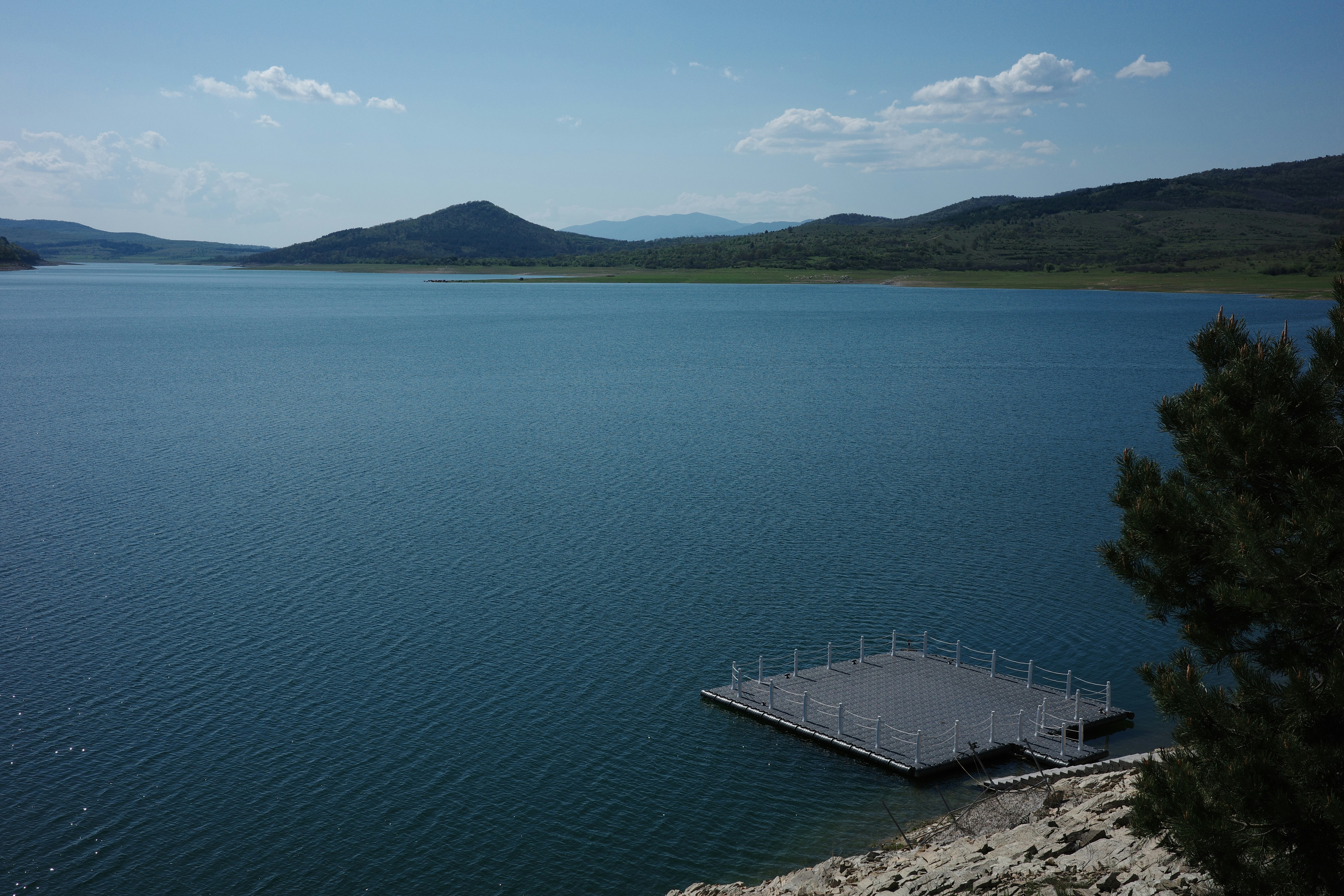 언덕이 있는 큰 파란 호수 위에 떠 있는 부두.