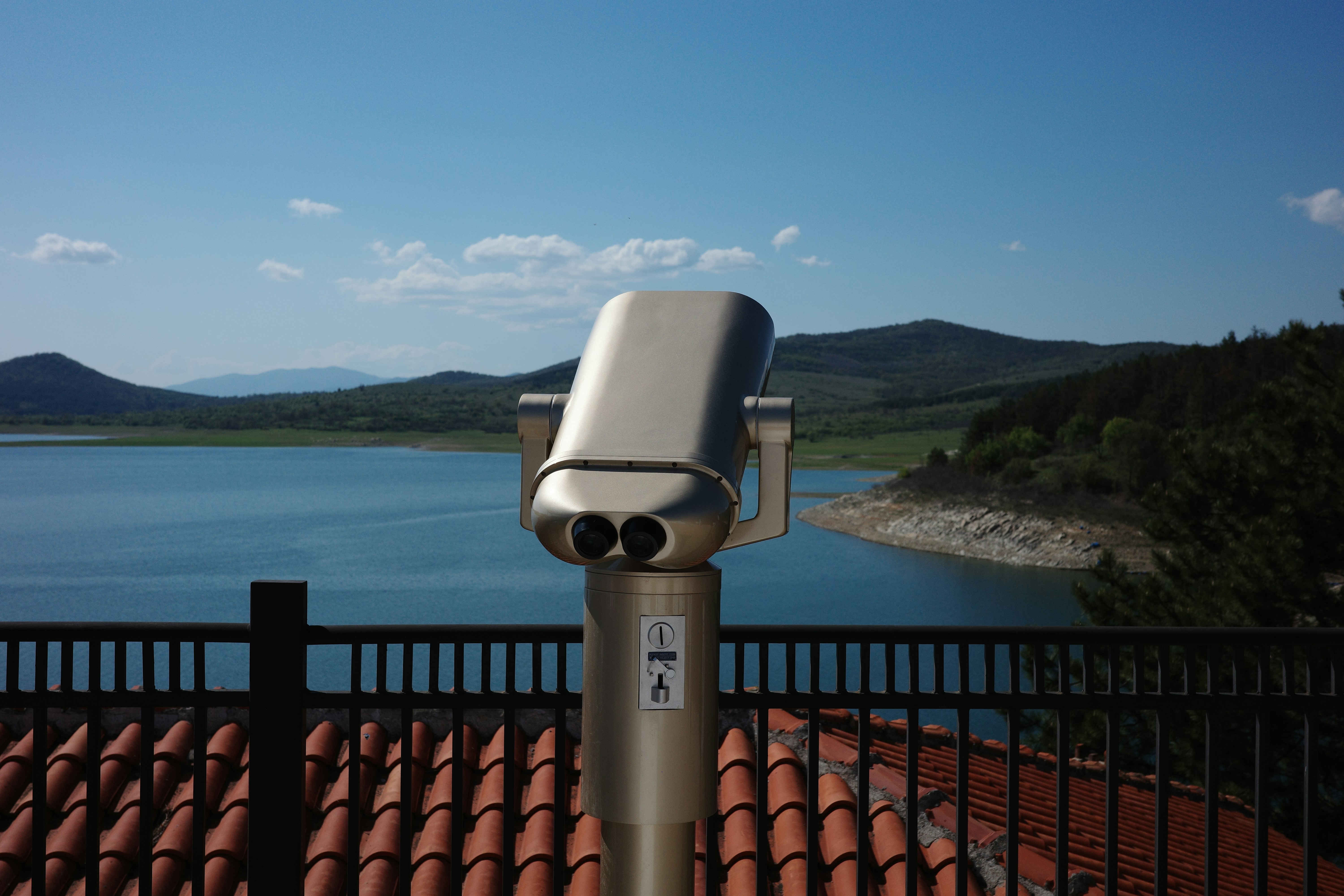 Binoculars overlooking a calm lake and rolling hills. 풍경 사진