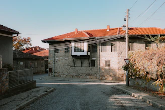 Stone house with red tiled roof and autumn trees