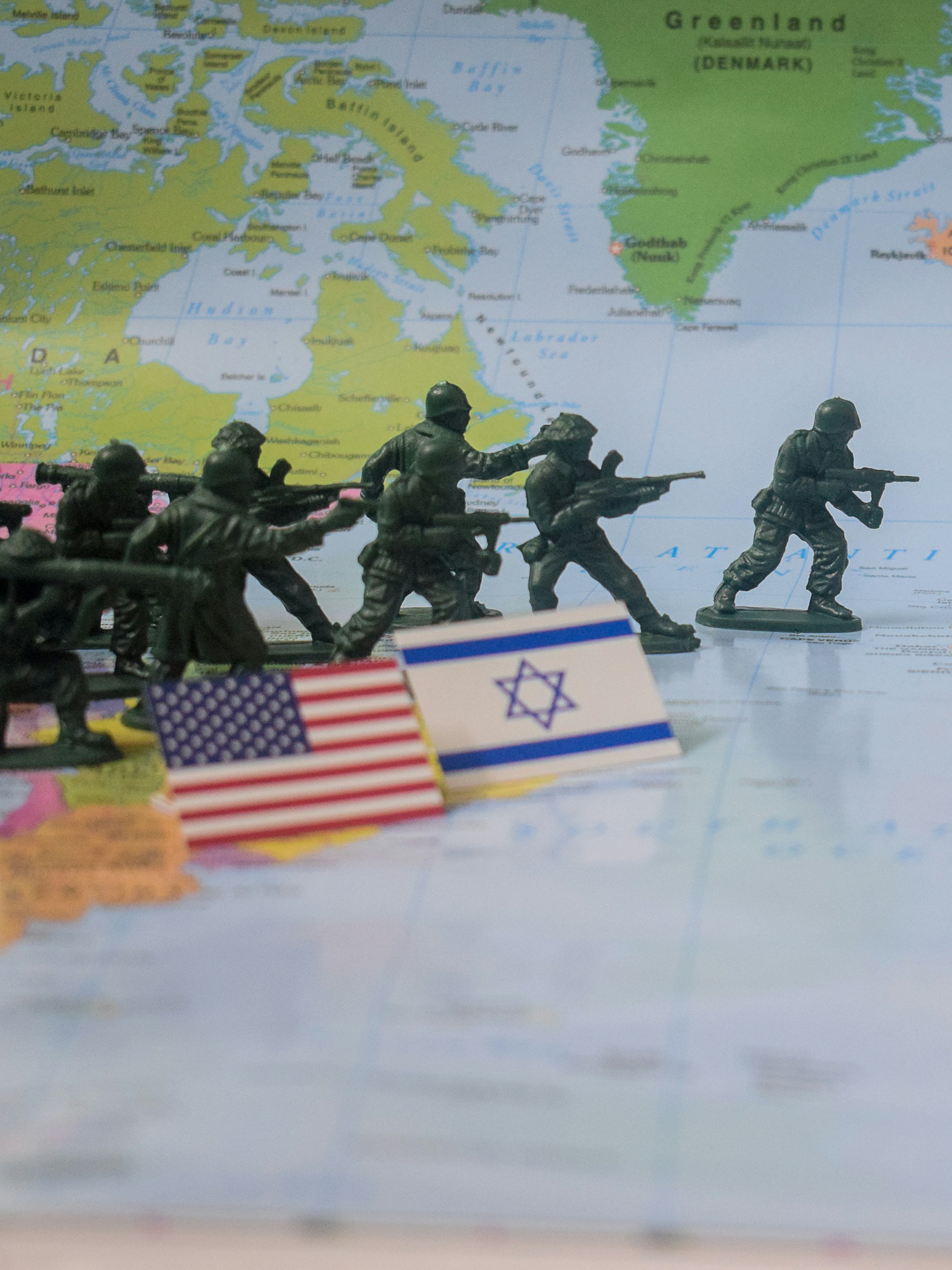 Toy soldiers advance past us and israeli flags on map.