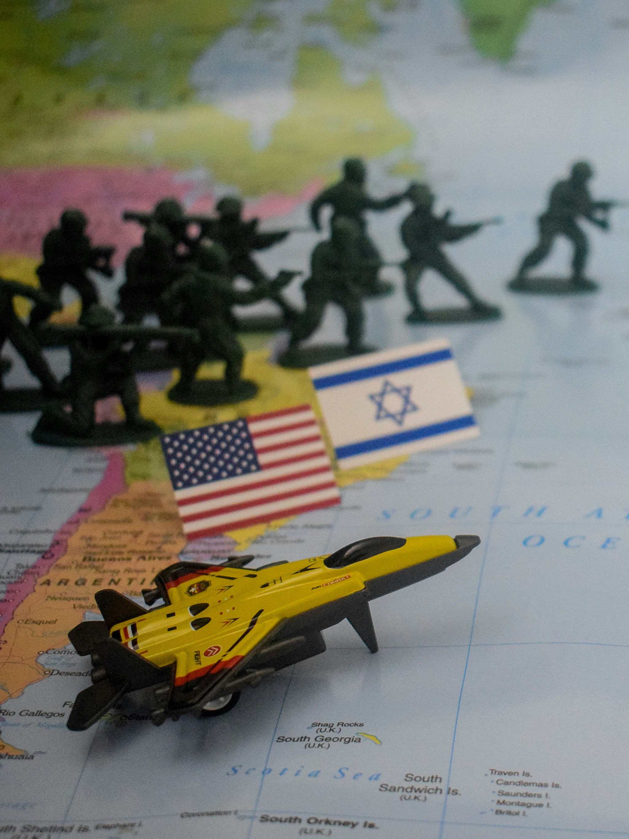 Toy soldiers, flags, and jet on world map.