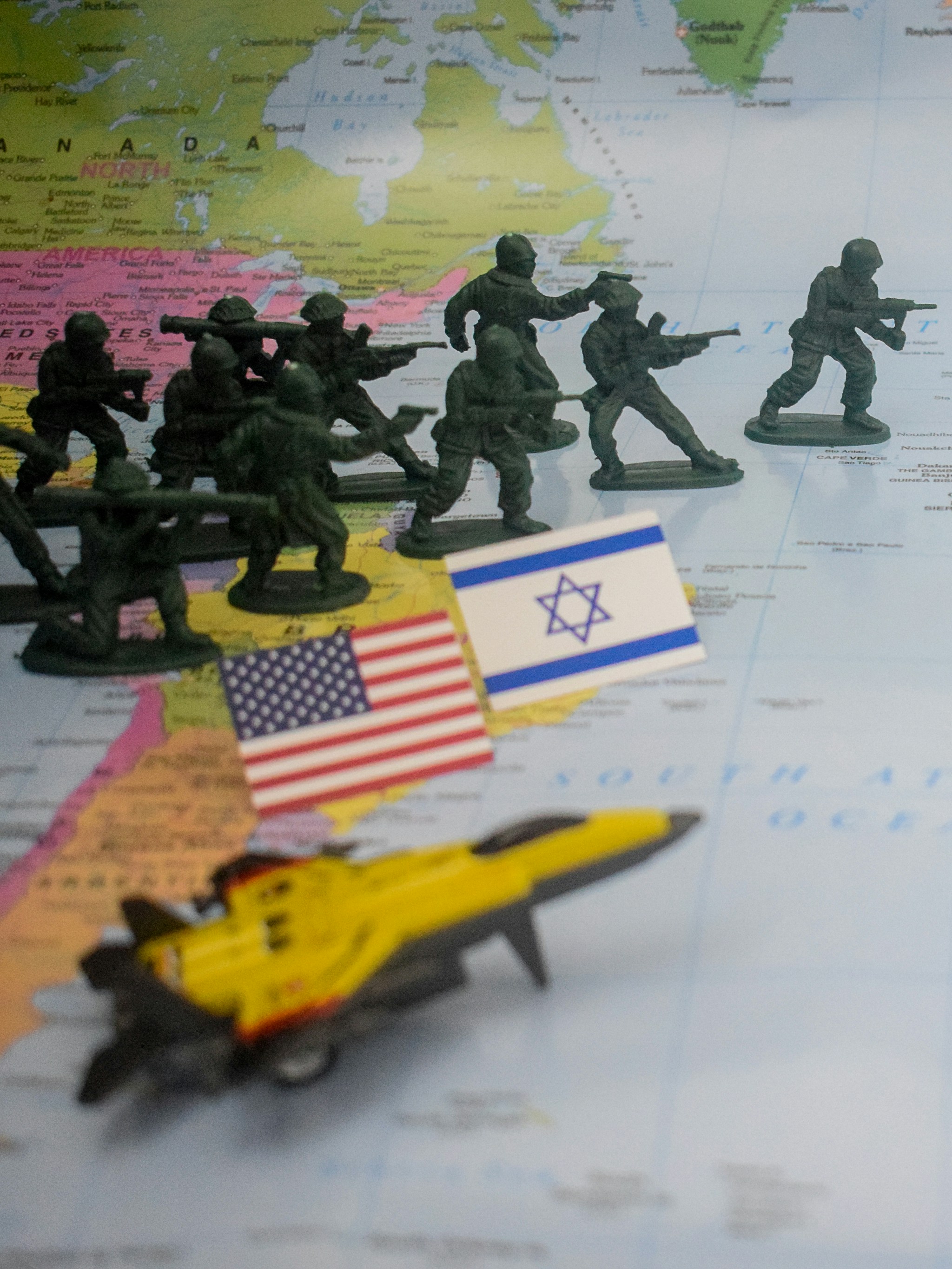 Toy soldiers and flags on world map with jet