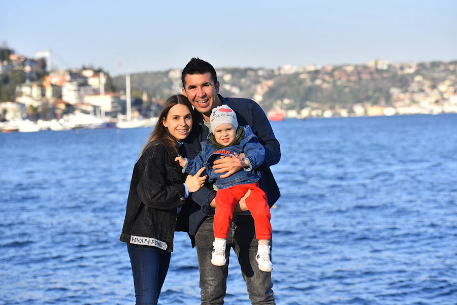 A family posing by the water with a city skyline in the background
