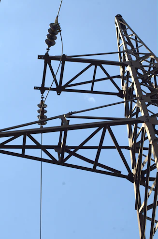 Close-up of a metal power line tower against blue sky