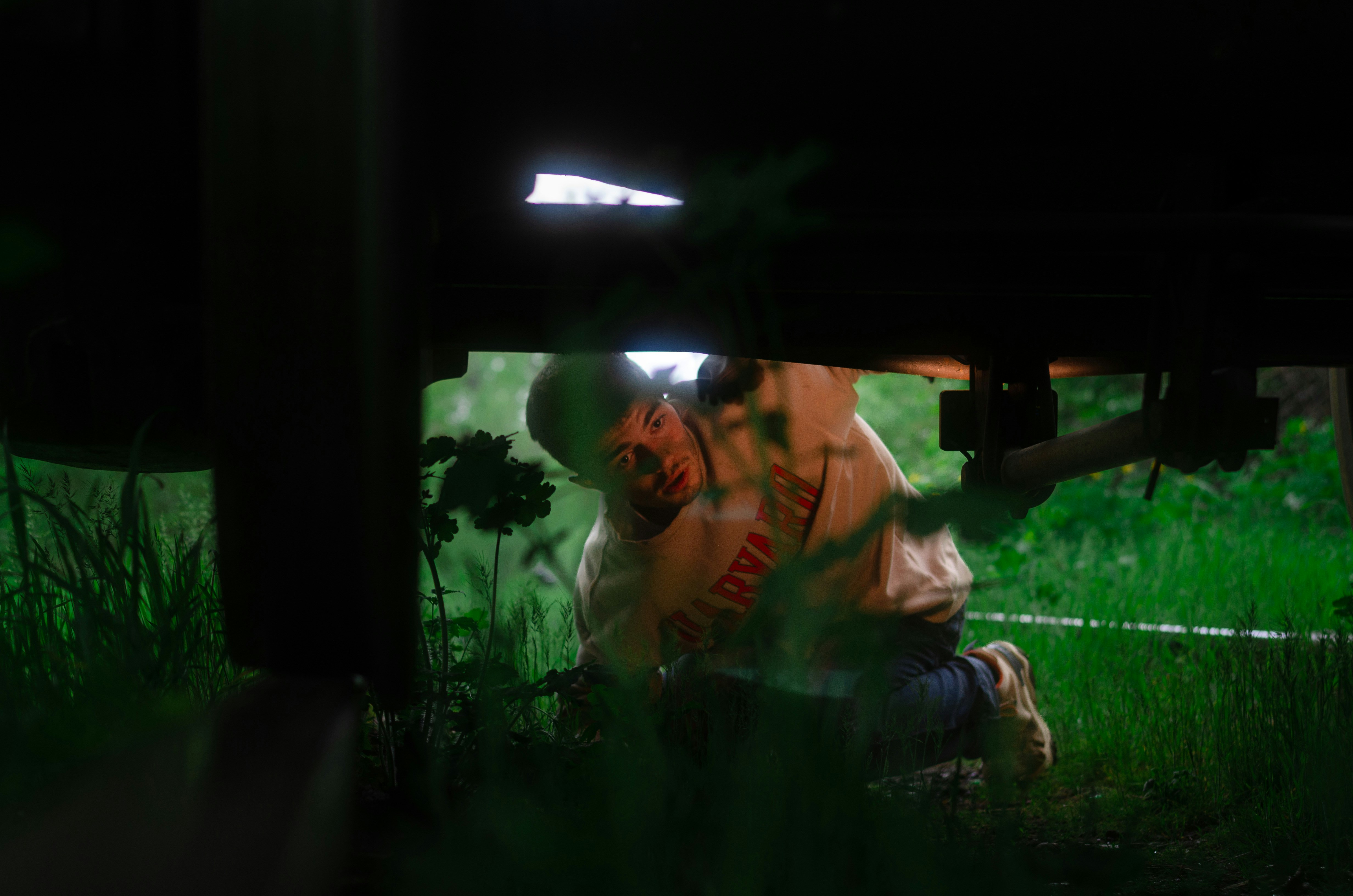 A person is hiding behind a wooden structure outdoors.
