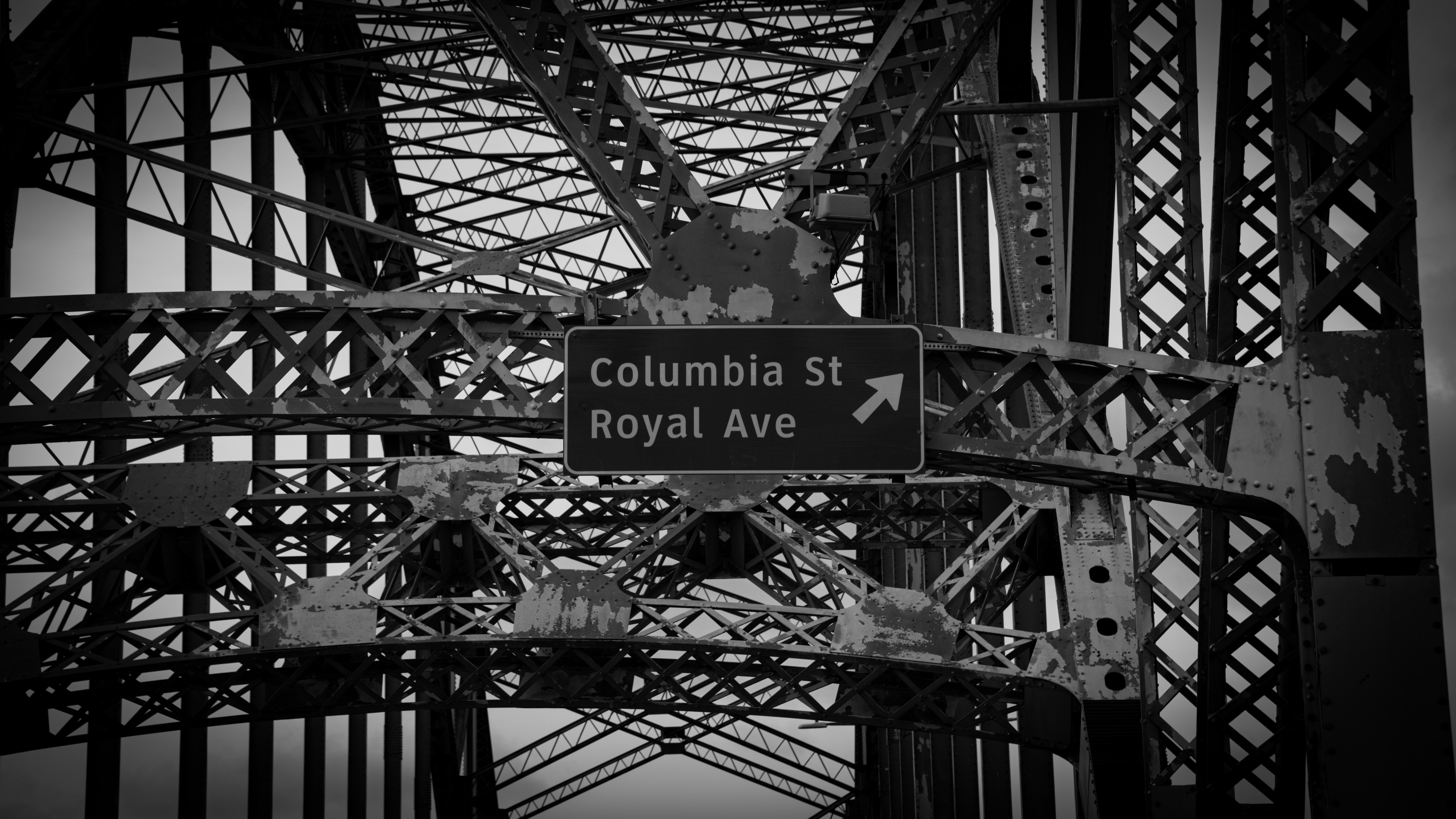 Black and white of a bridge with street signs.