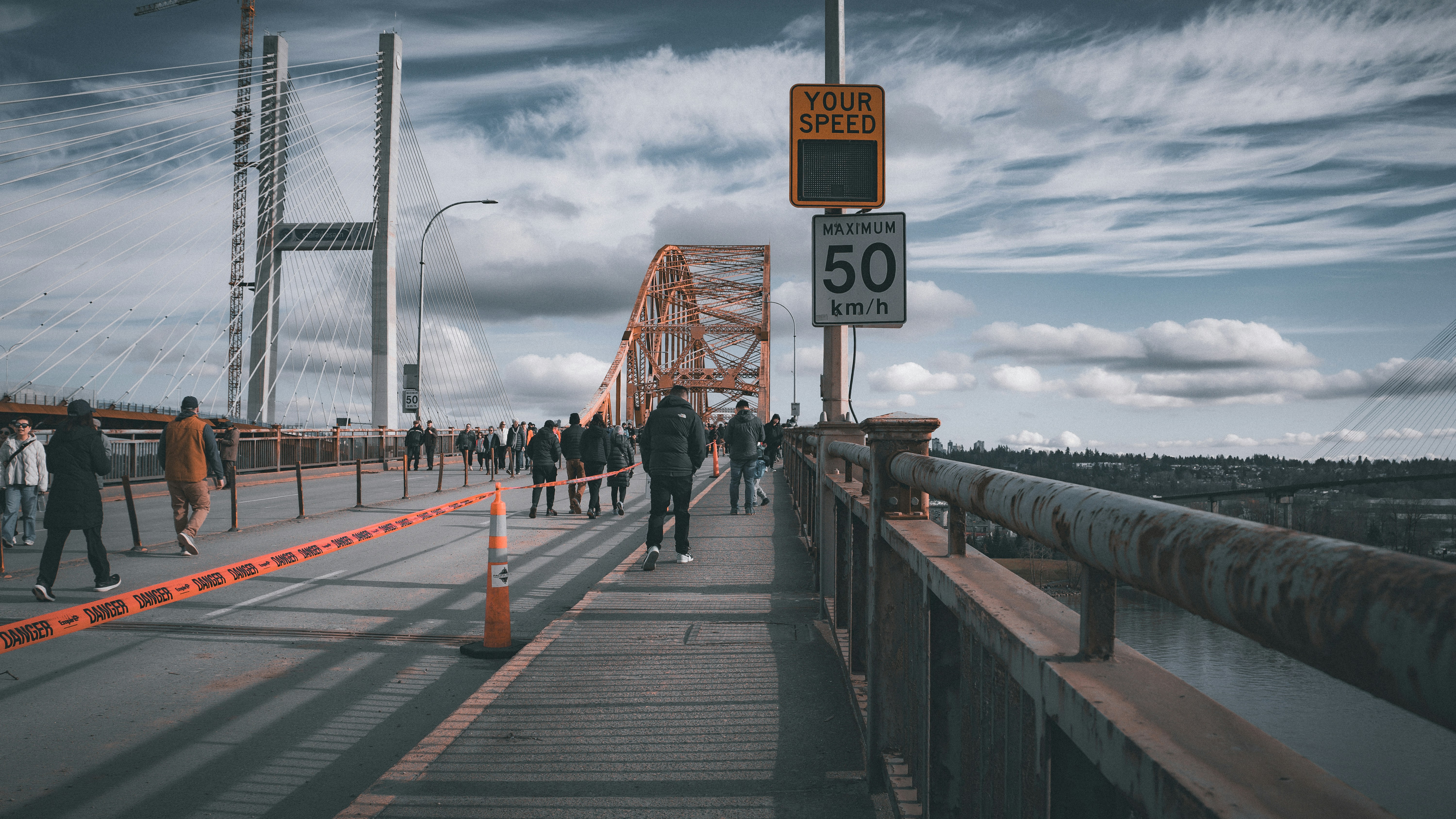 People walking on a bridge with cars in the background