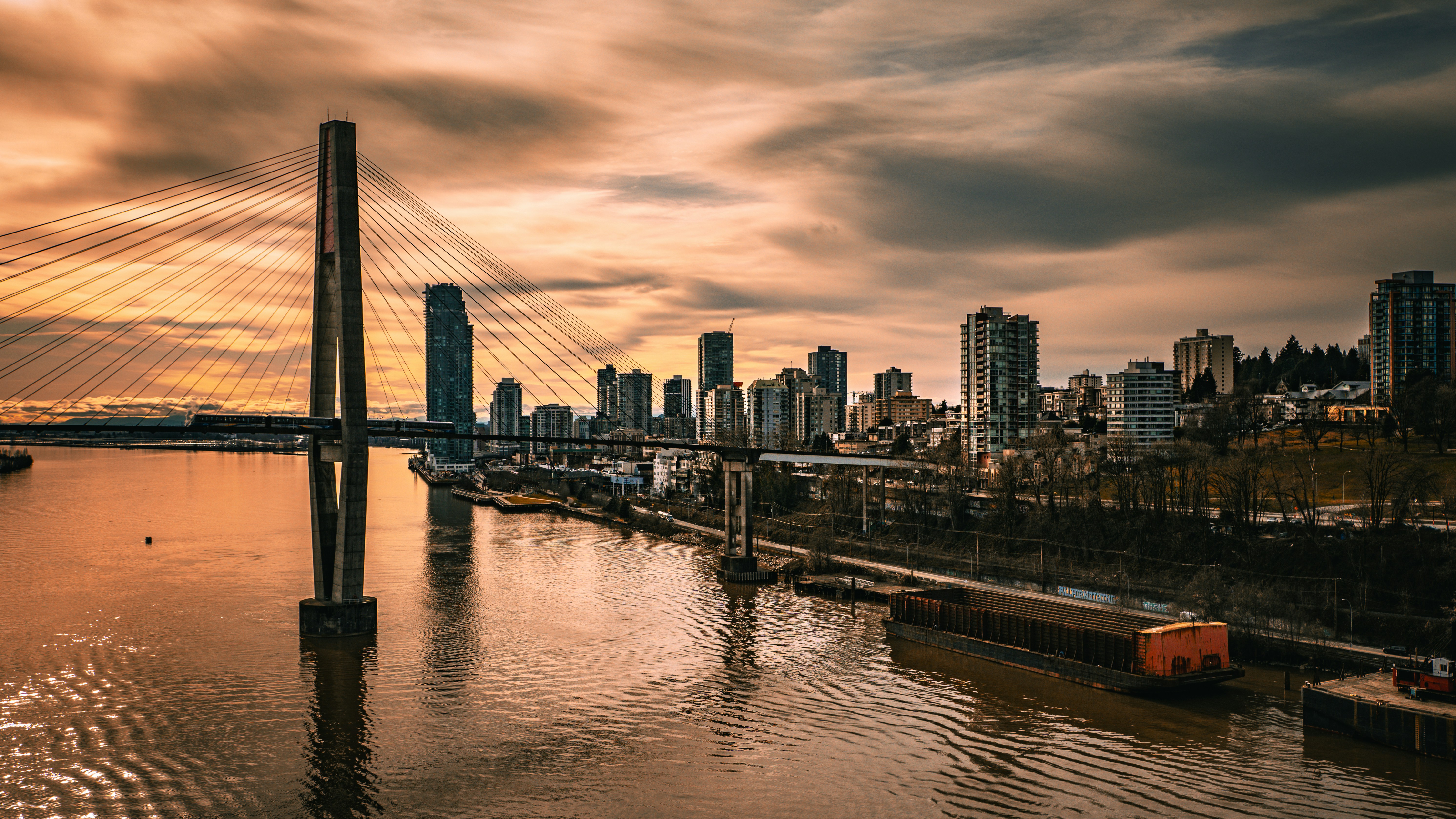 City skyline with bridge over water at sunset