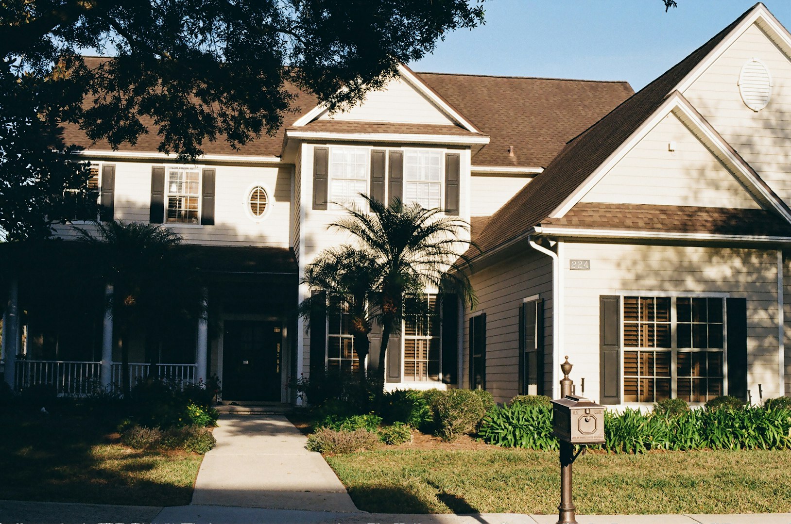Large two-story home with a covered porch and palm tree at the entry