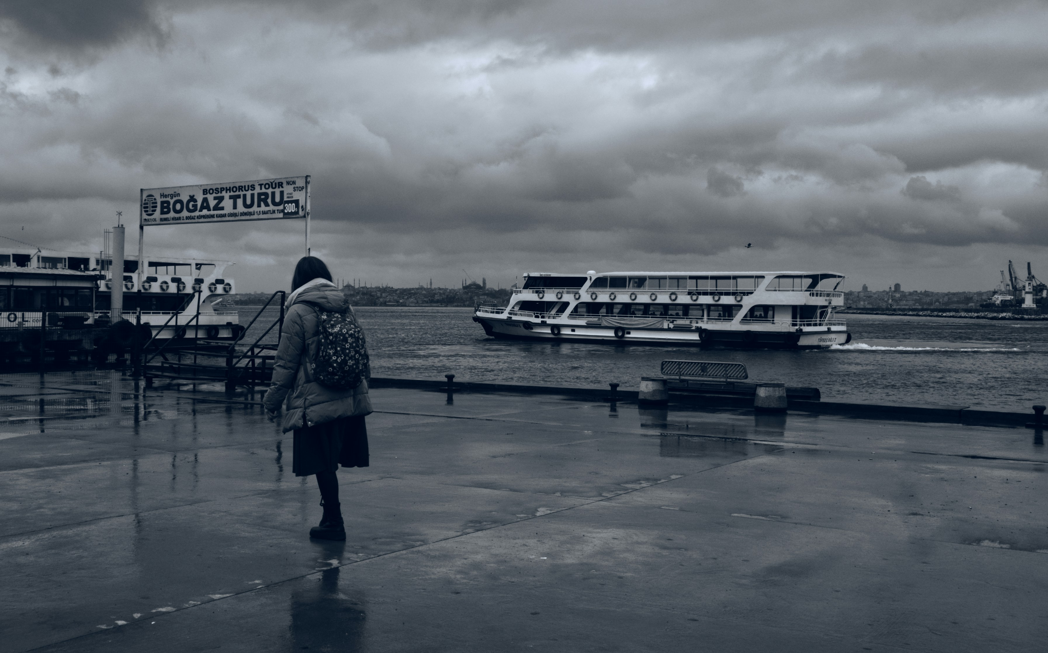 Persona che cammina sul molo bagnato con un traghetto sullo sfondo