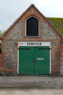 Brick building with green double doors and "service" sign.