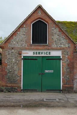 Brick building with green double doors and "service" sign.