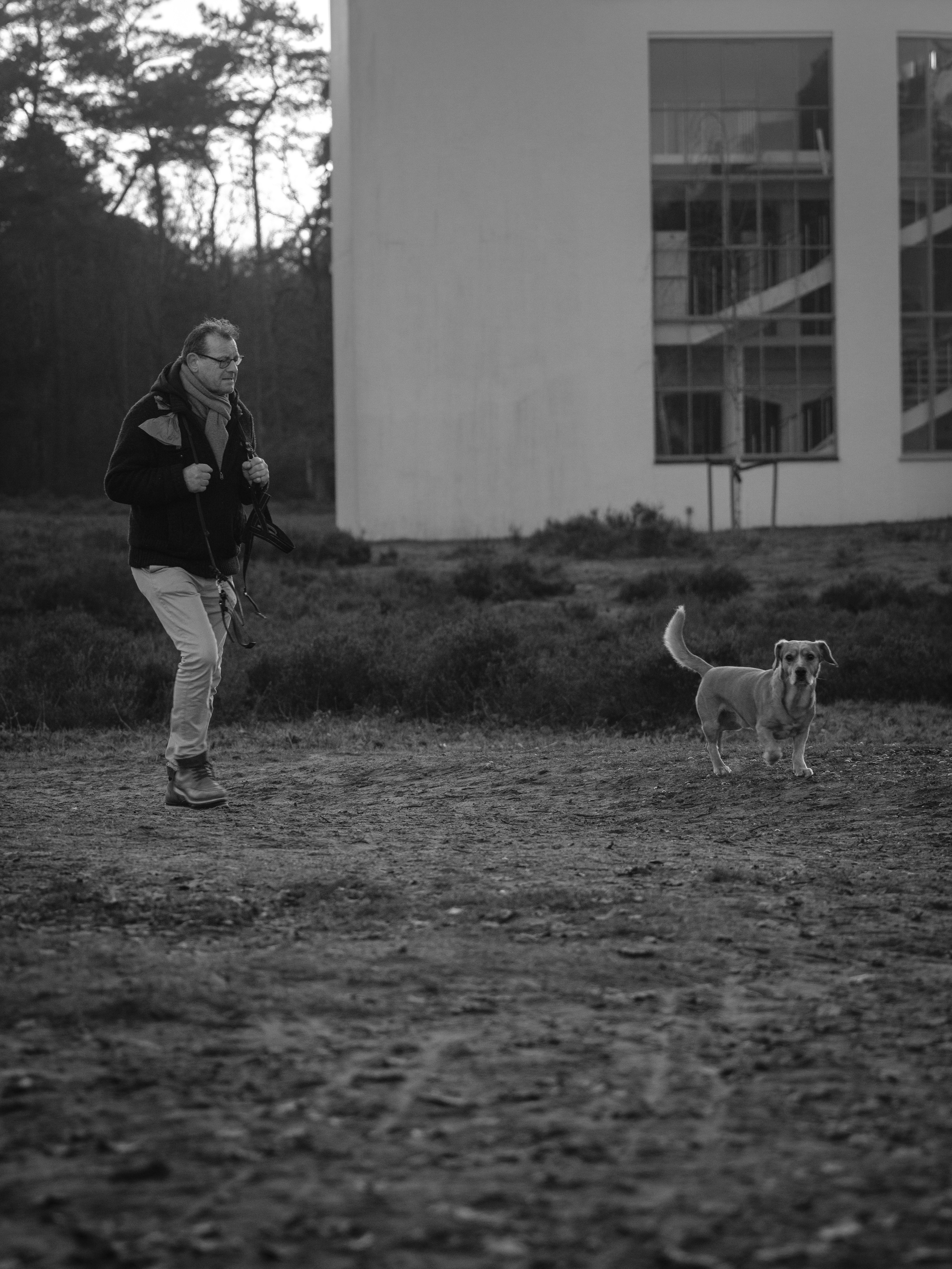 Man walking a dog near a modern building