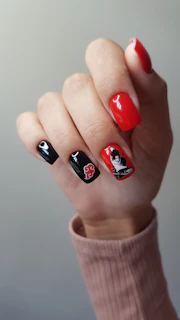 Hand with black and red nails featuring anime characters.