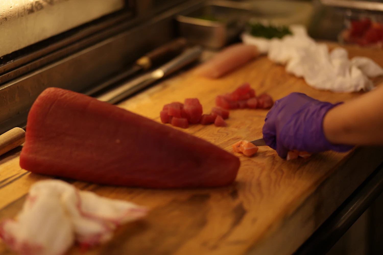 Chef using a kitchen knife on a wooden cutting board during food preparation