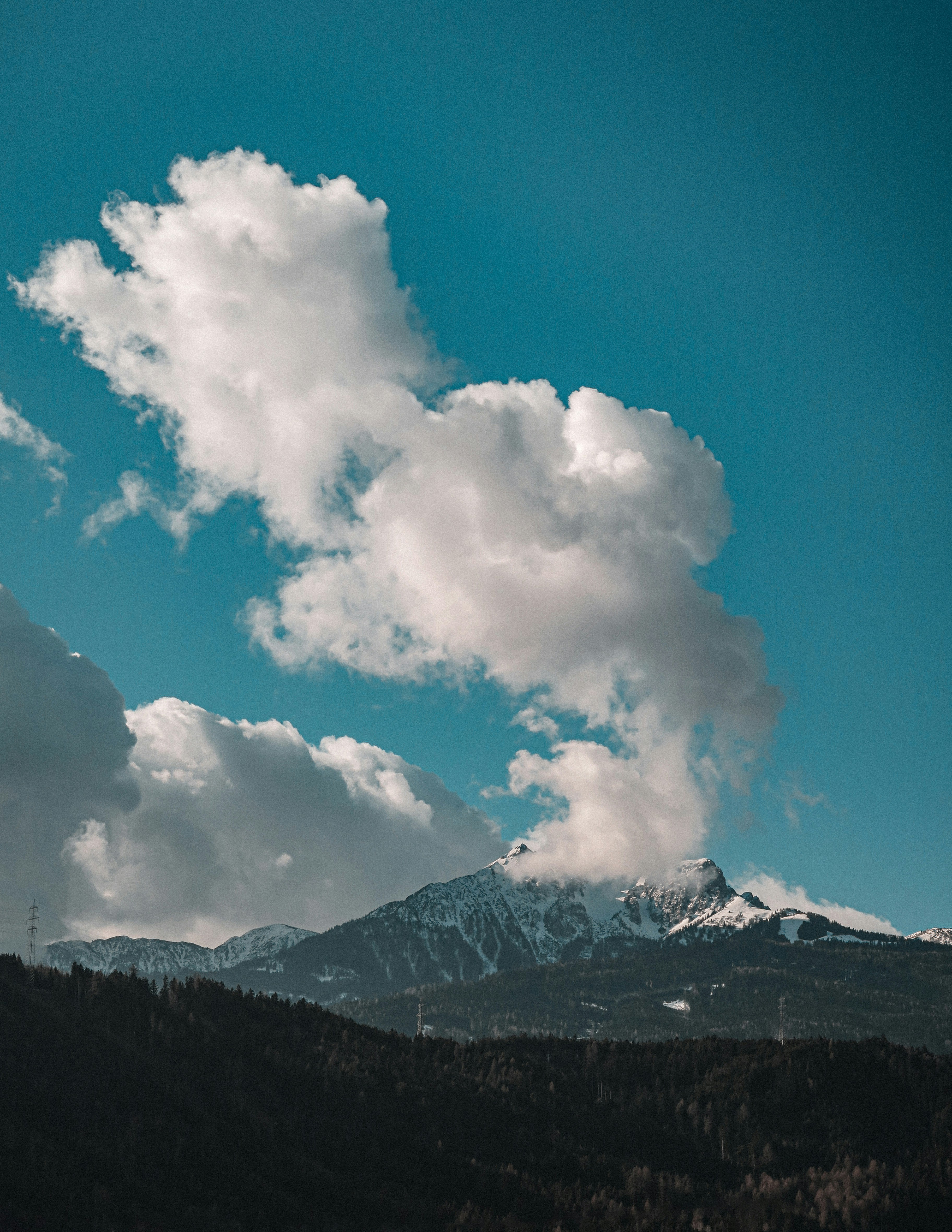 Un pico montañoso nevado emerge de las nubes