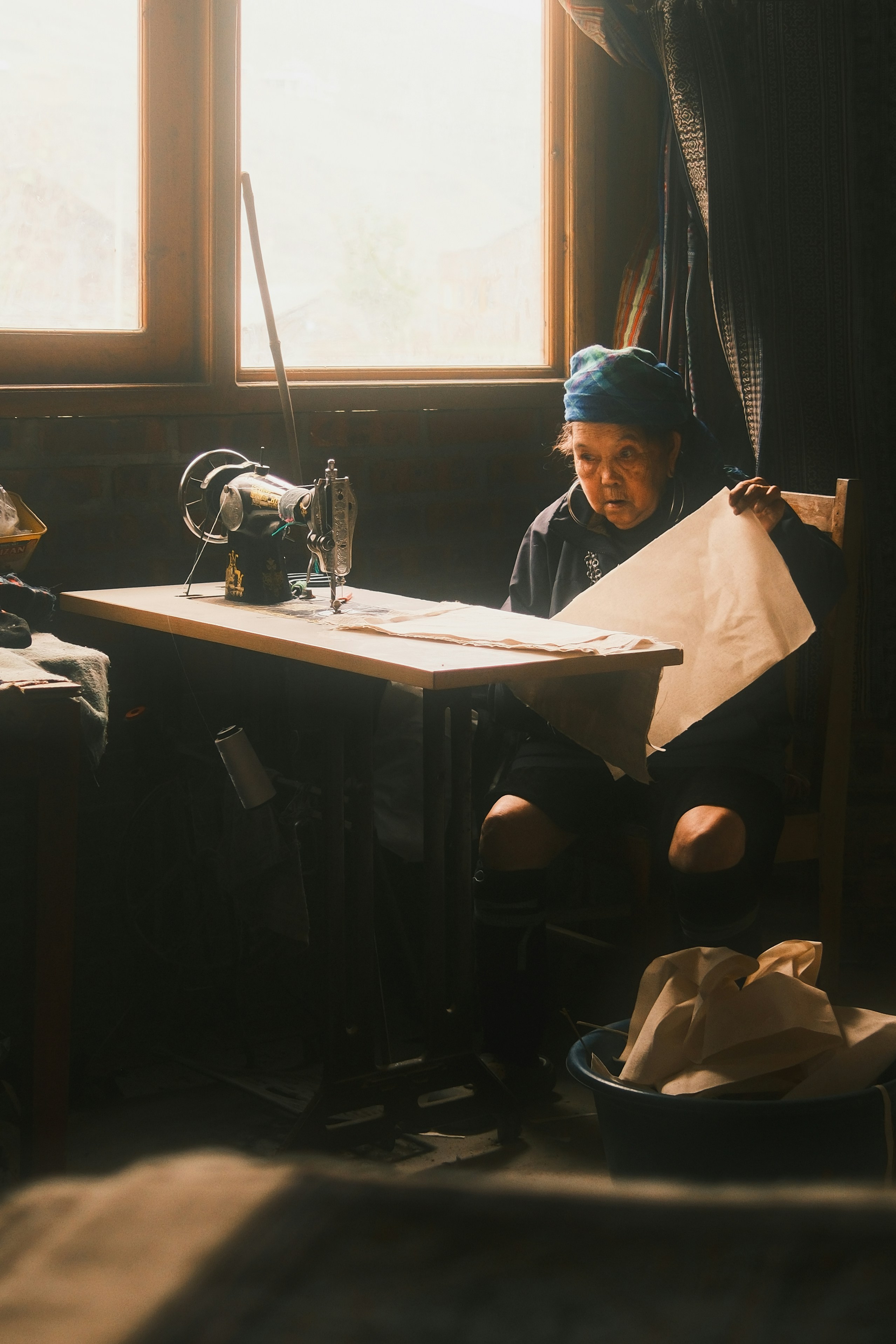 Elderly woman sewing with a vintage sewing machine.