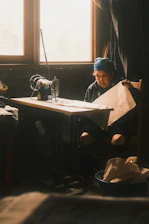 Elderly woman sewing with a vintage sewing machine.