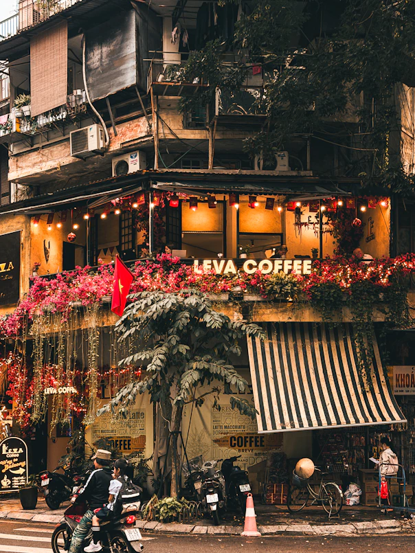 A coffee shop with flowers and lights on a street.