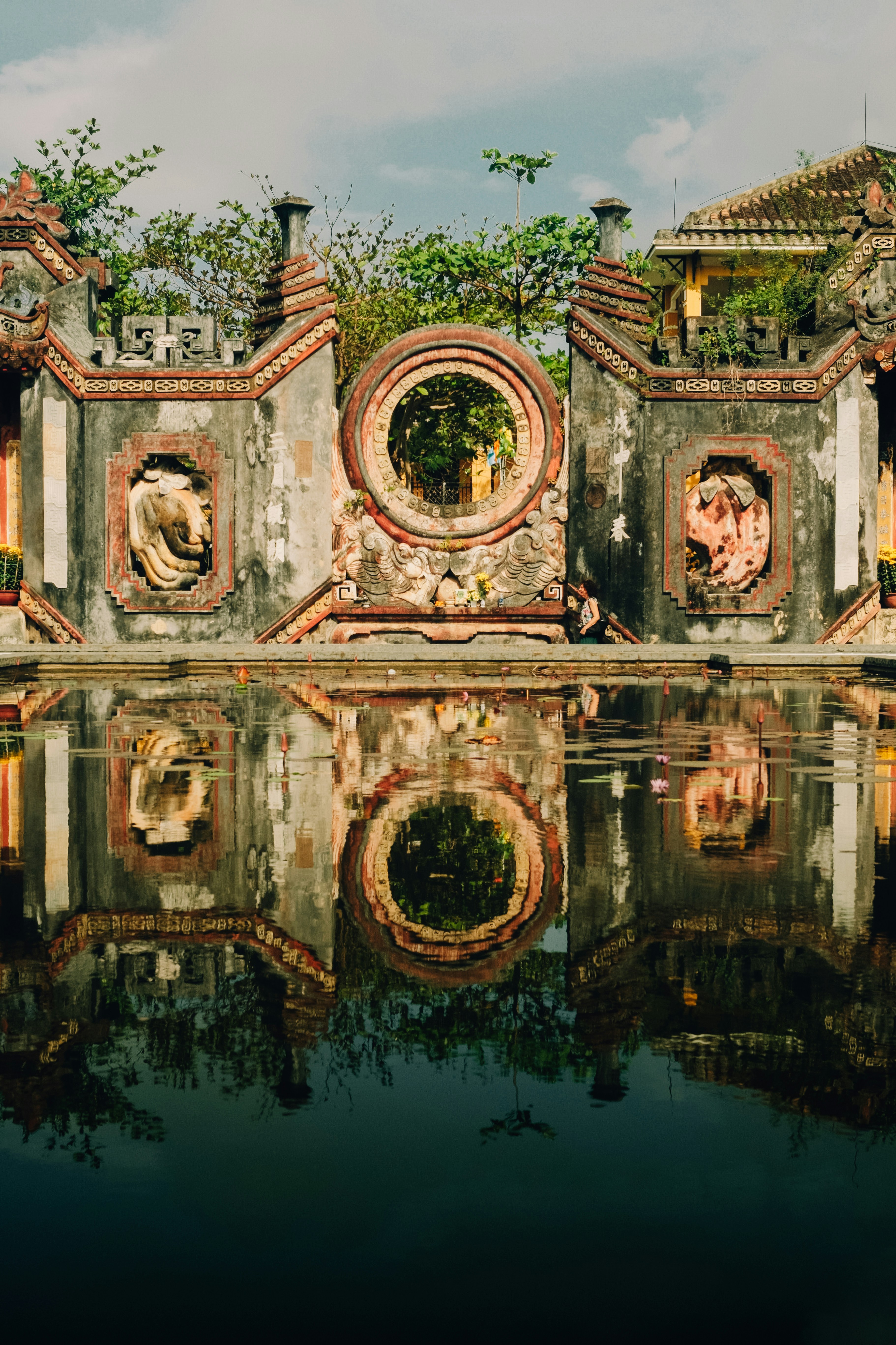 Ornate weathered wall with circular window reflected in water