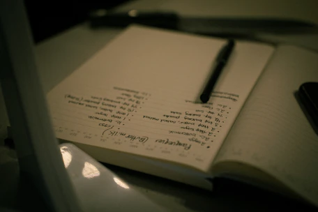 A pen rests on an open notebook with handwritten notes.