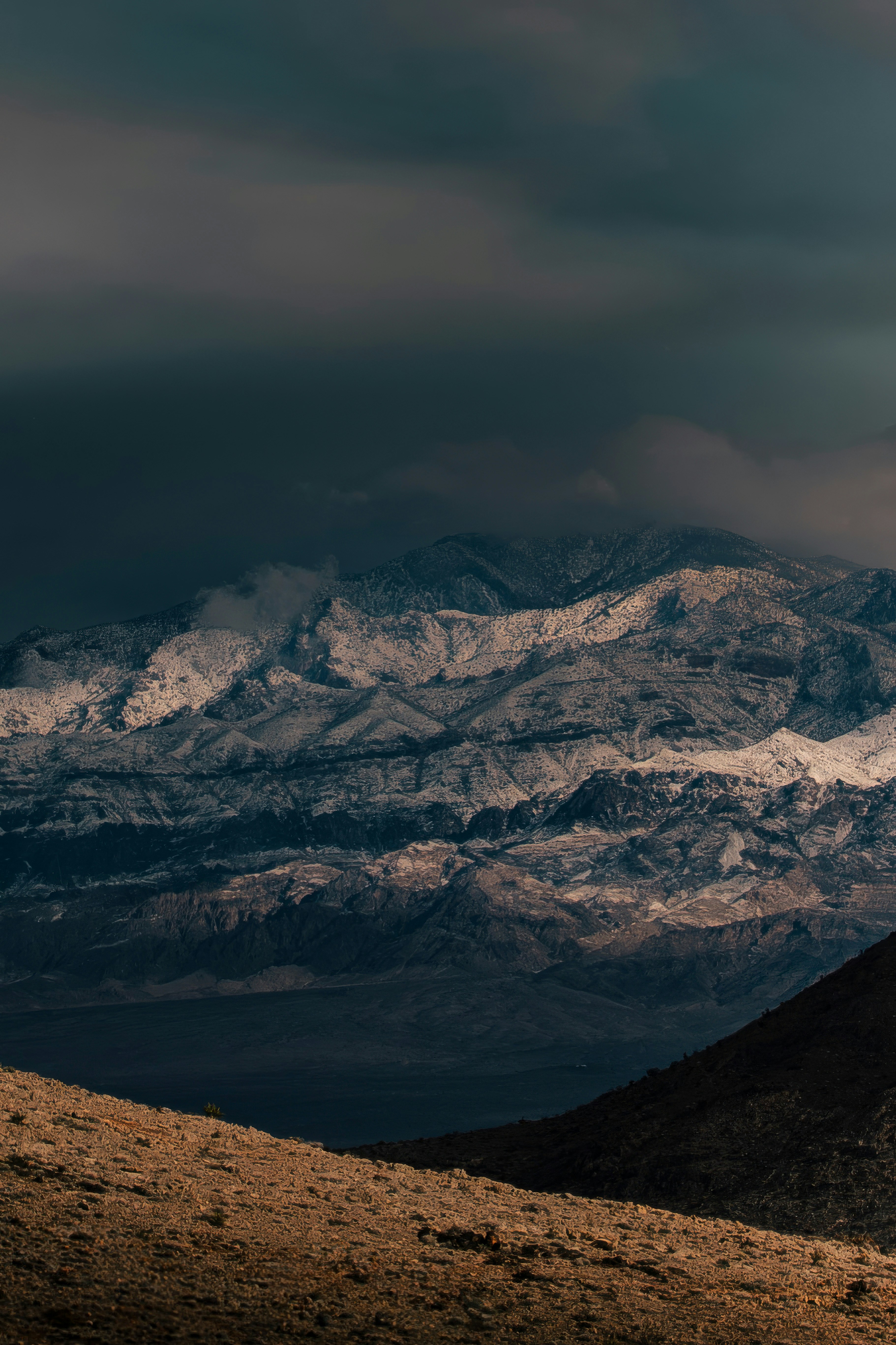 Snow-capped mountains under dark, dramatic clouds.