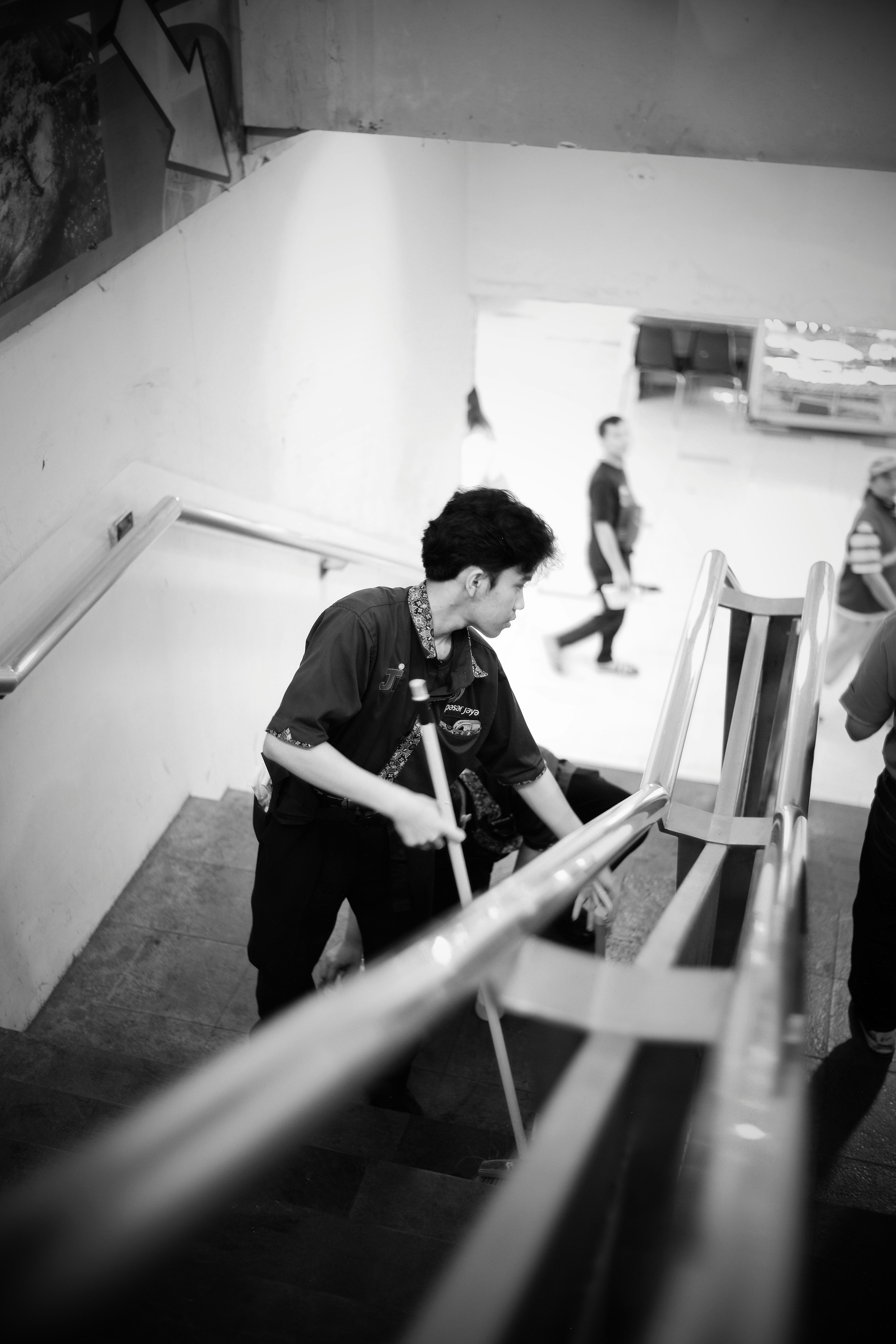 Man walks down stairs holding a broom