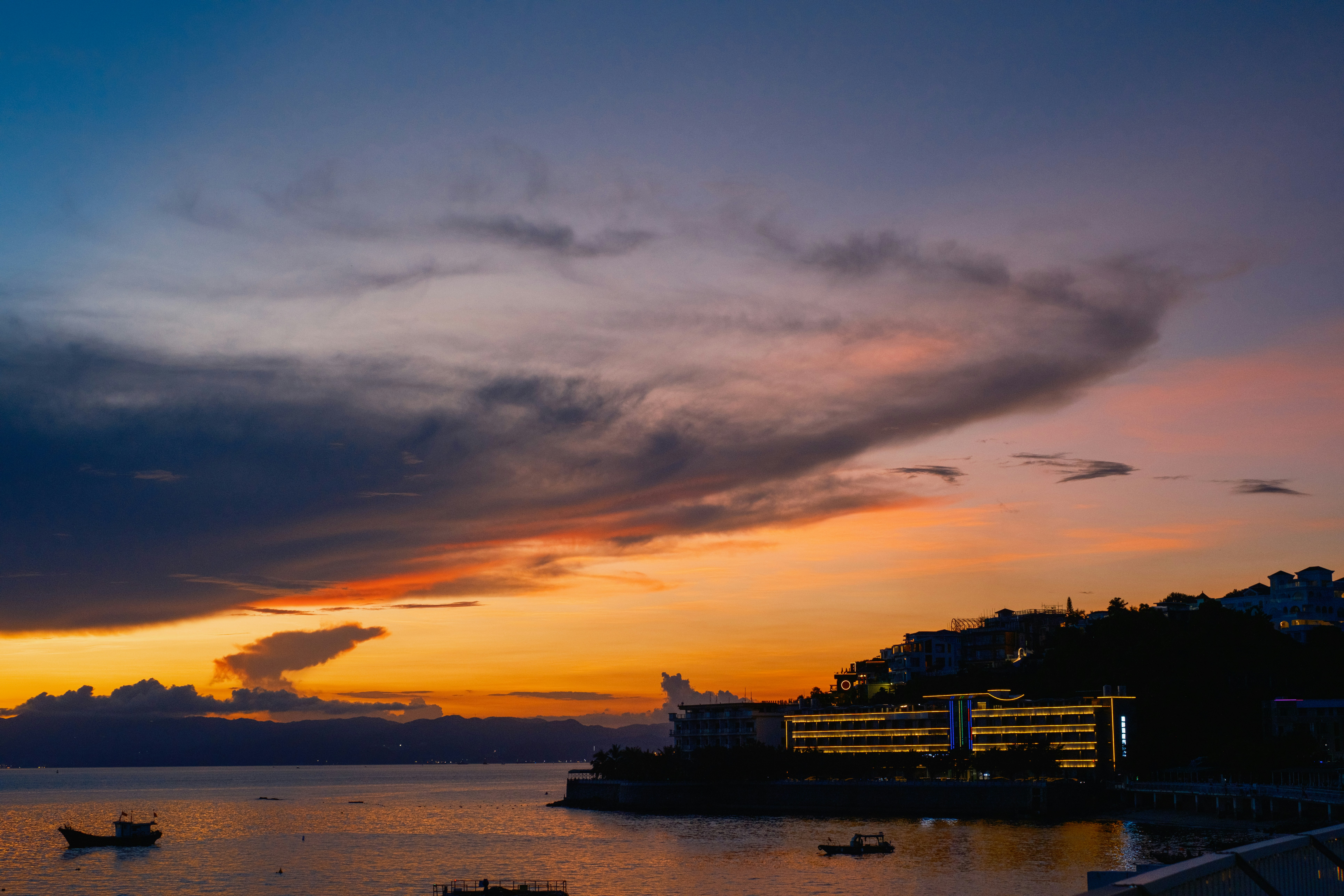 船が停泊する海岸沿いの町に劇的な夕焼け。