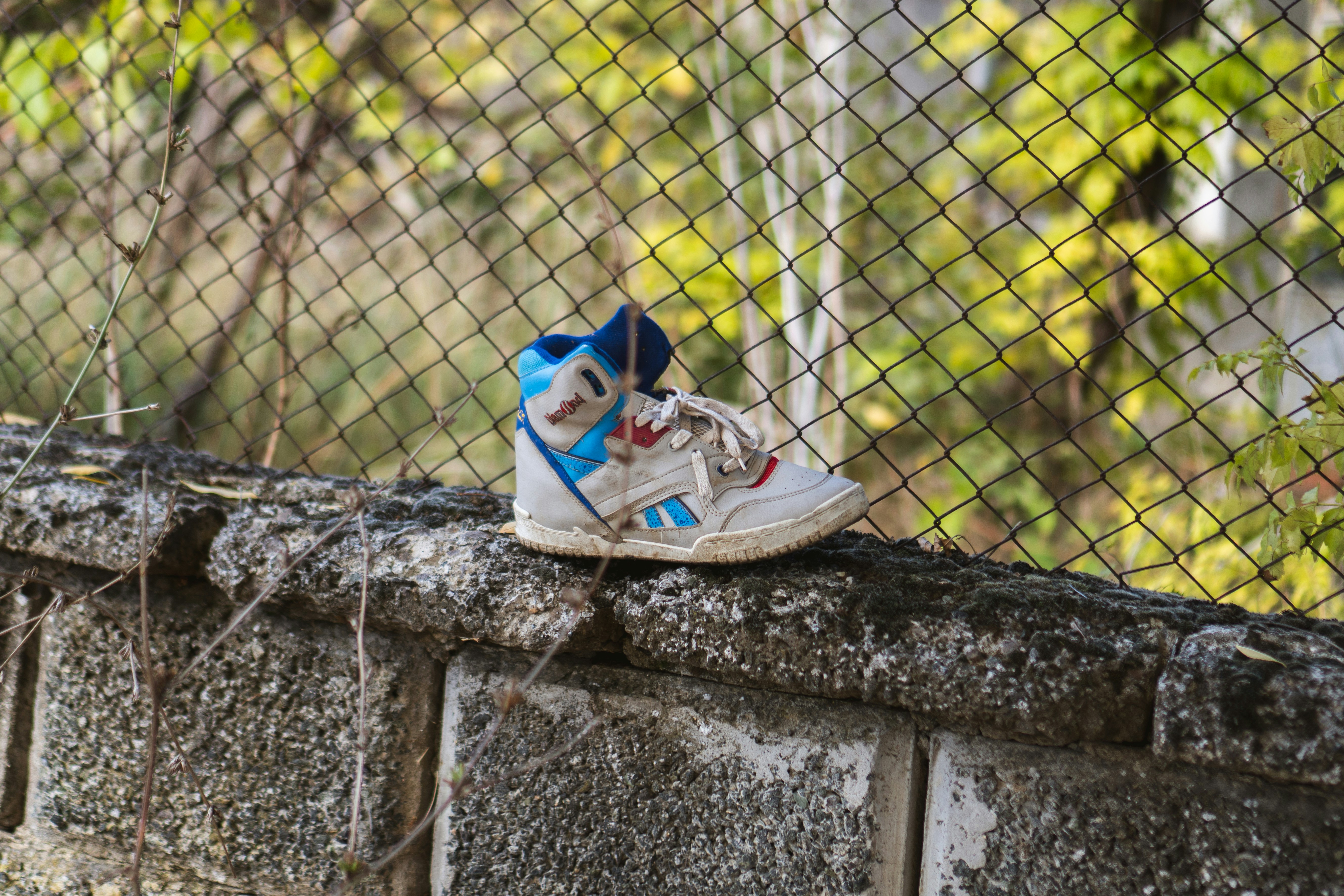Um tênis de criança repousa em uma parede de concreto.