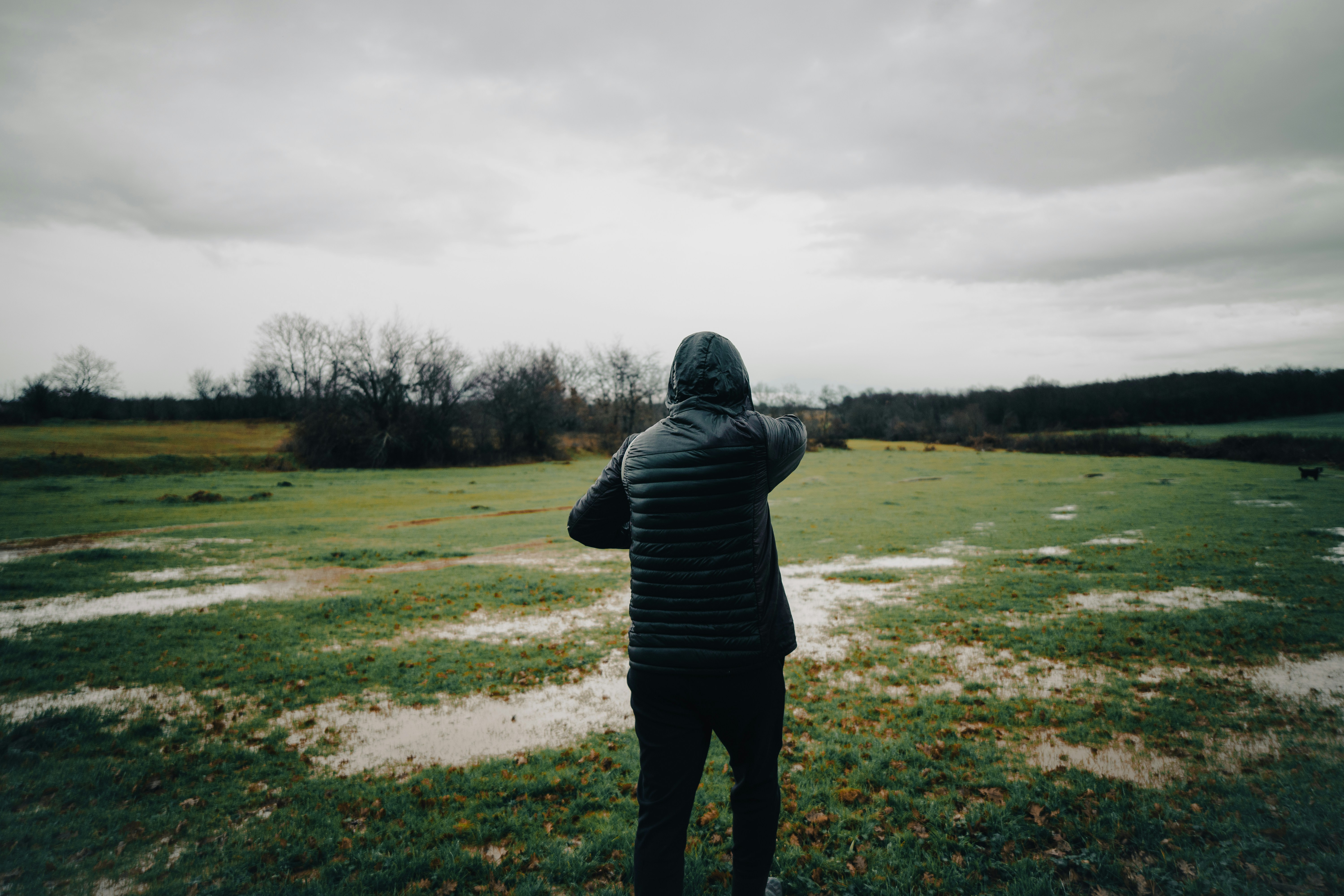 Person in hooded jacket looking at flooded field