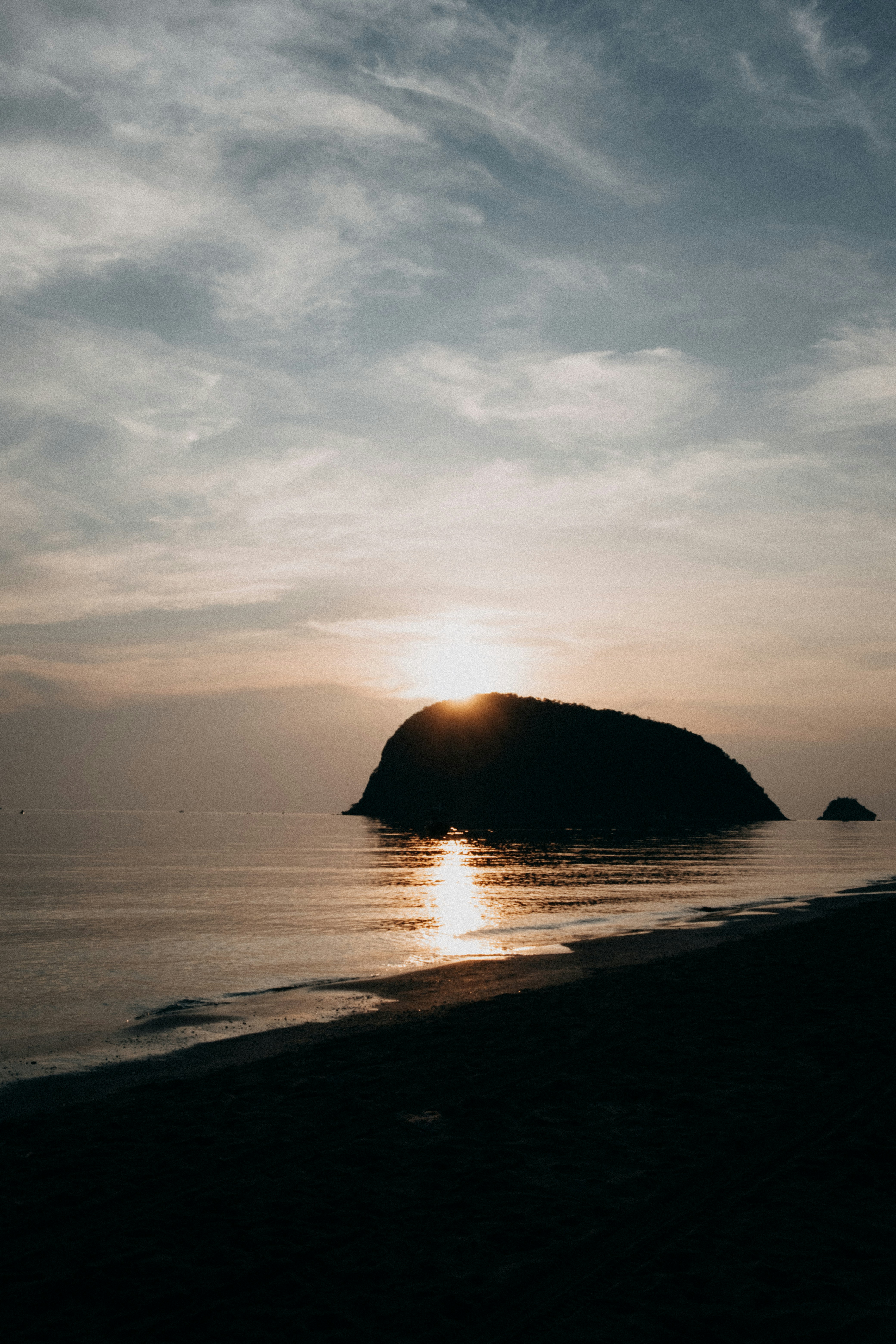 Sunset behind a silhouetted island on the ocean.