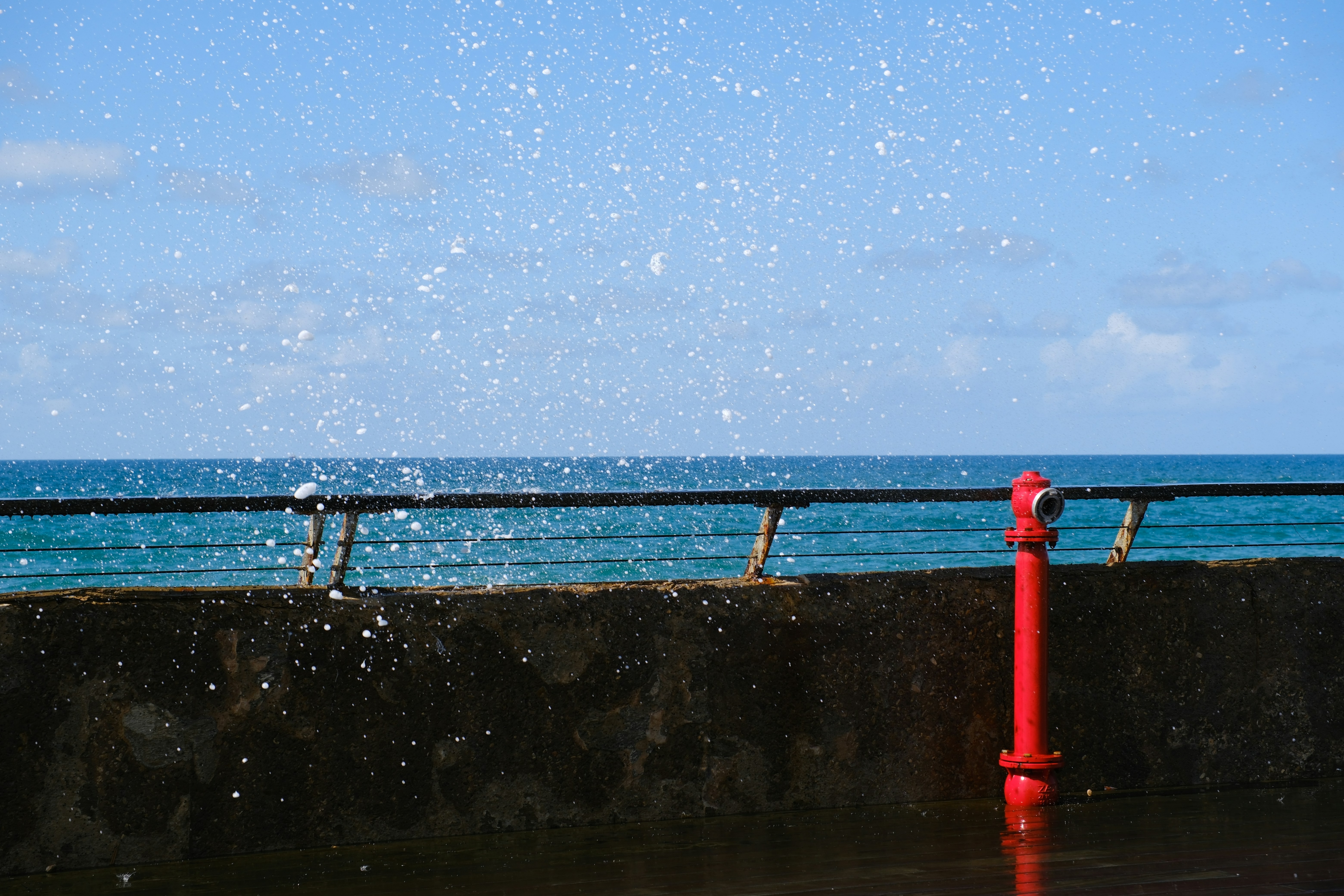 Red fire hydrant by the sea with splashing water