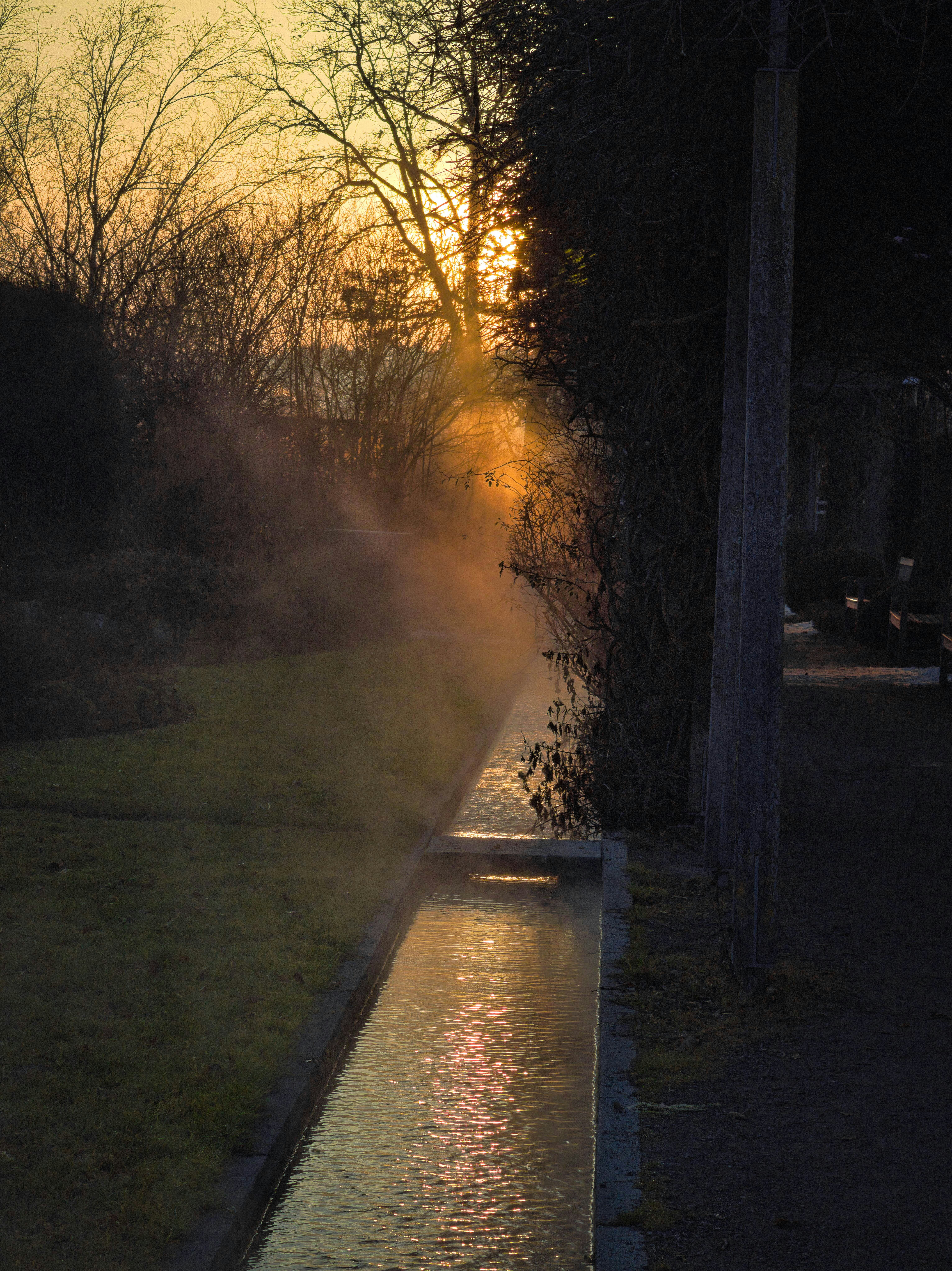 Bei Sonnenuntergang steigt Dampf aus einem Kanal auf