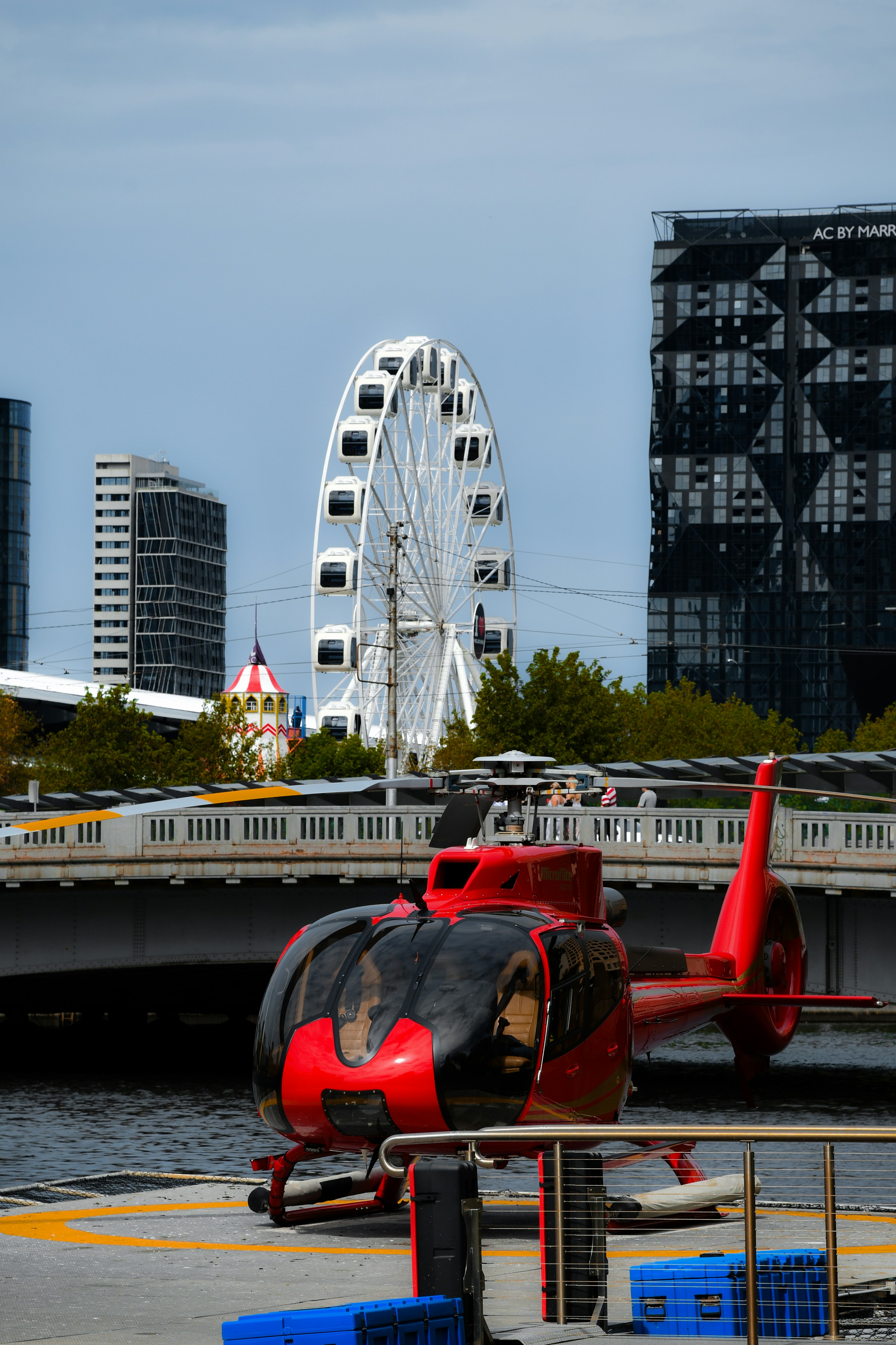 Red helicopter on a helipad with ferris wheel background