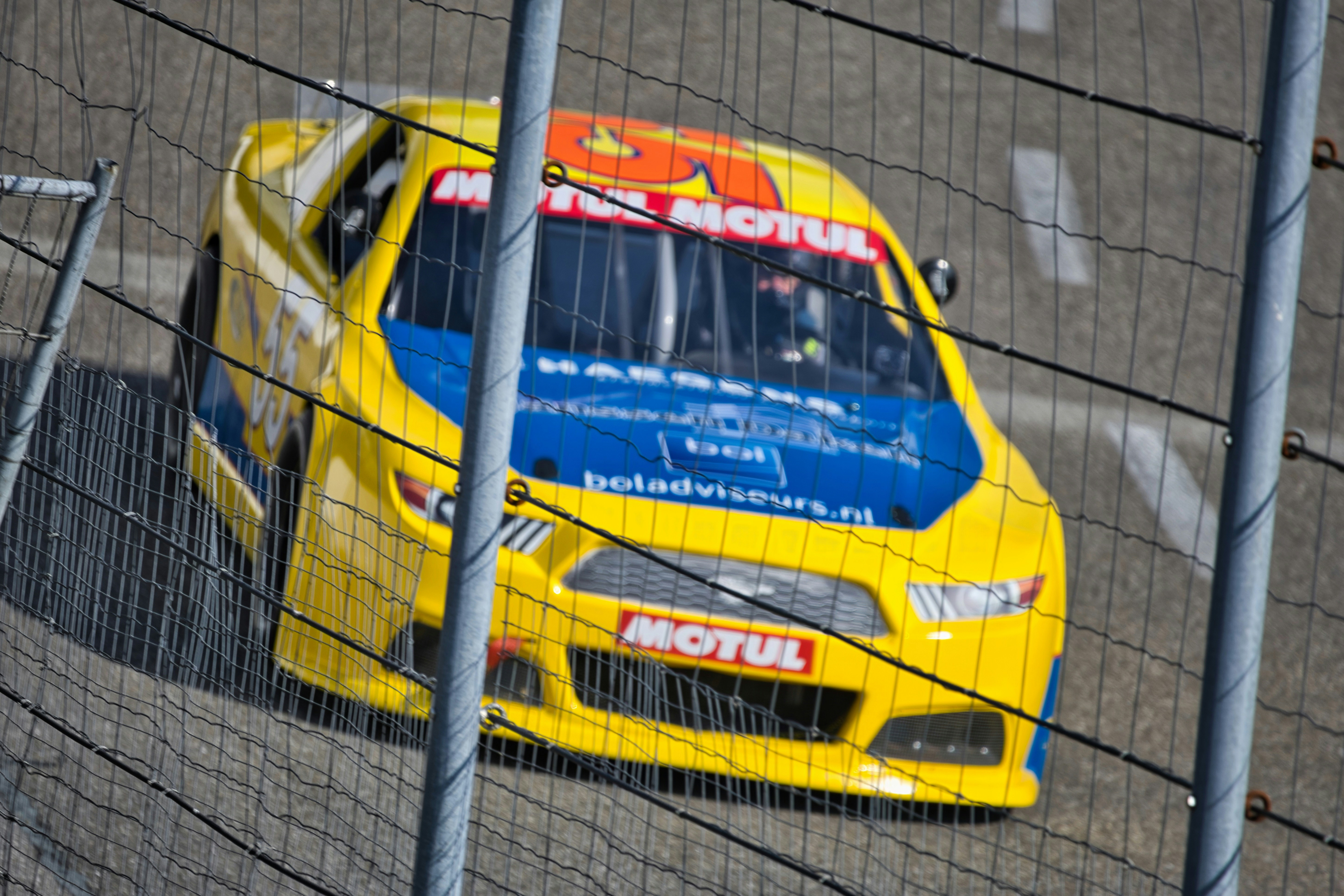 Ein gelb-blaues Rennauto, das über eine Strecke rast.