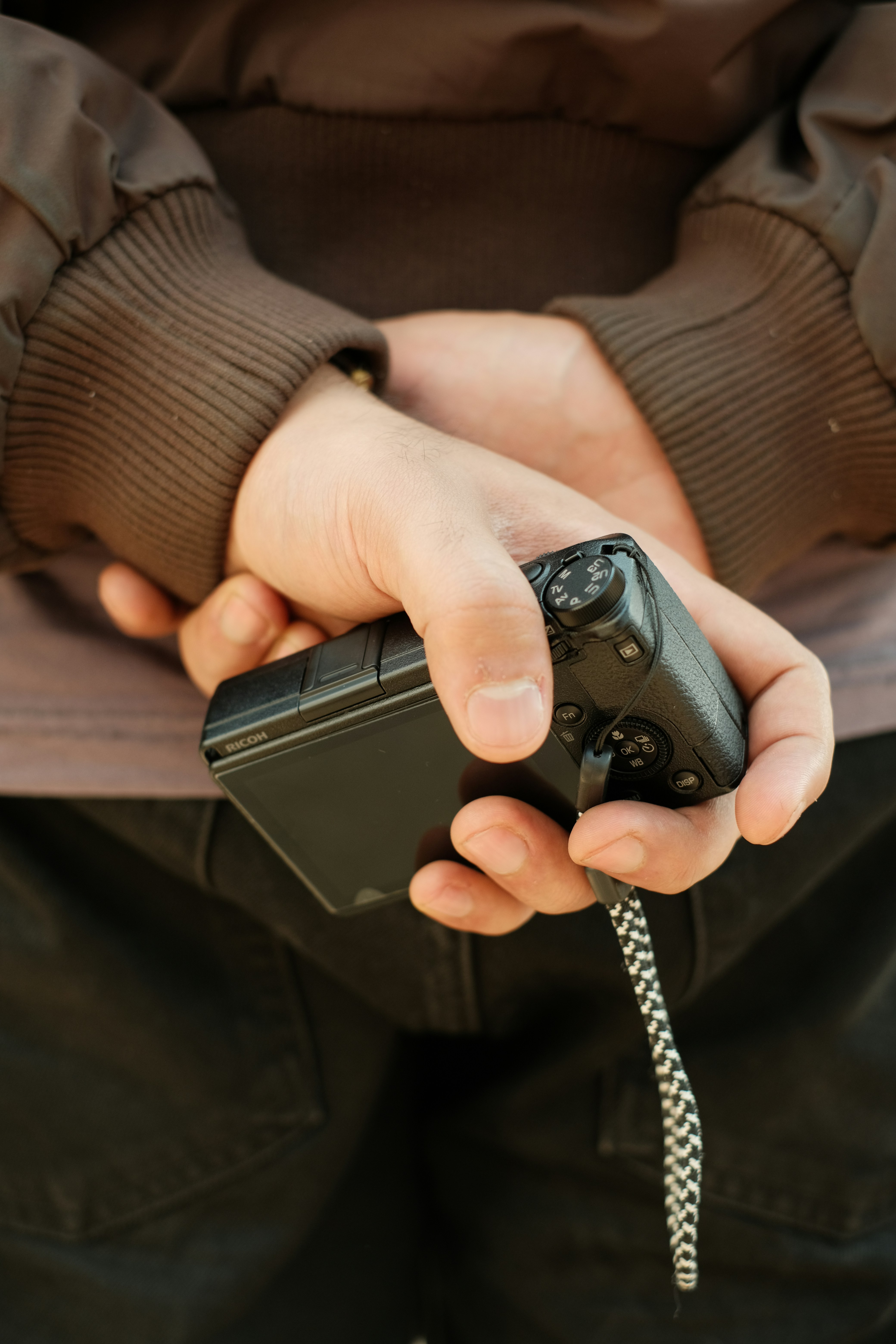 Mãos segurando uma câmera digital compacta