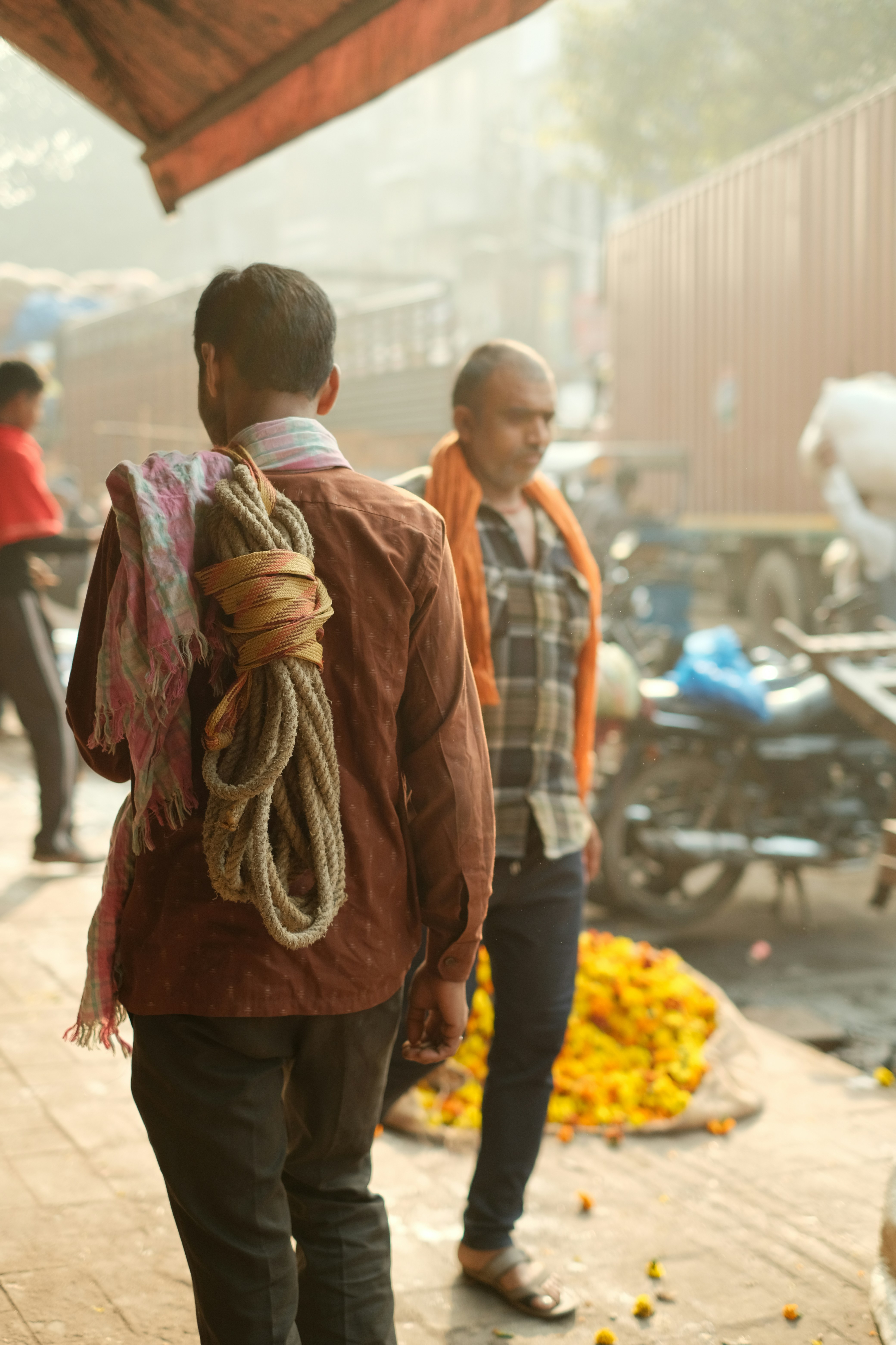 Dois homens caminhando por um mercado ao ar livre movimentado.
