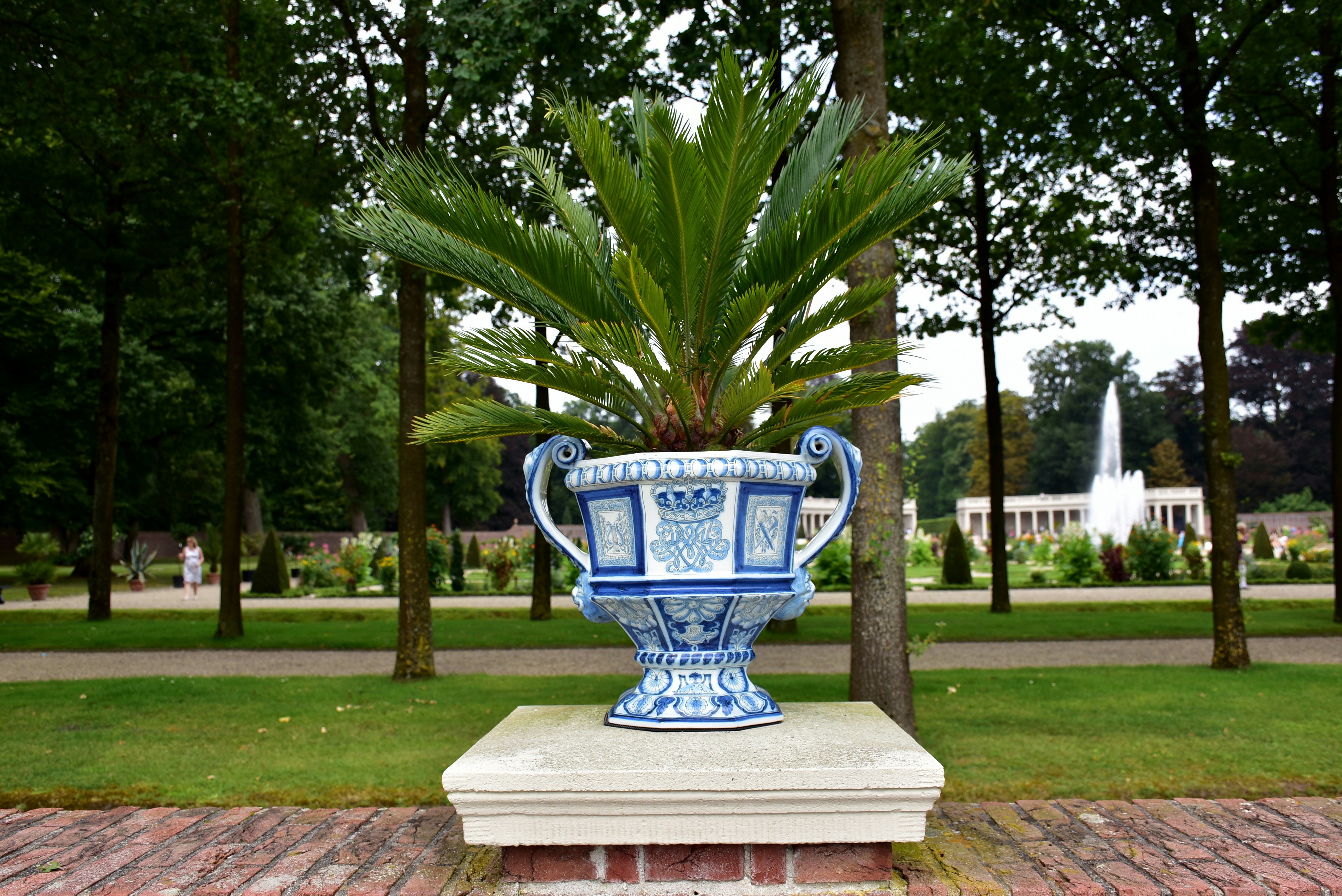 Ornate vase holding a palm plant in a garden