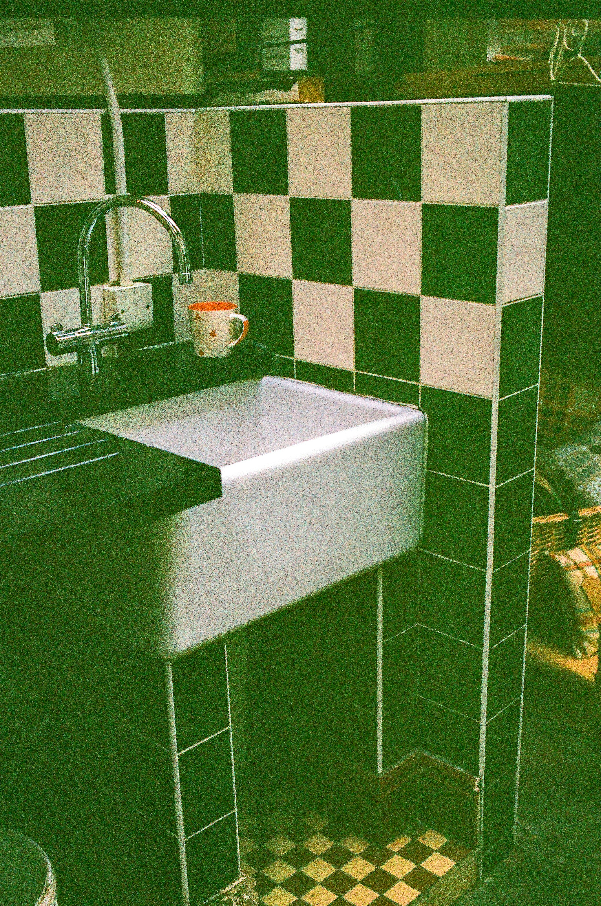 Sink with checkered tile backsplash and floor