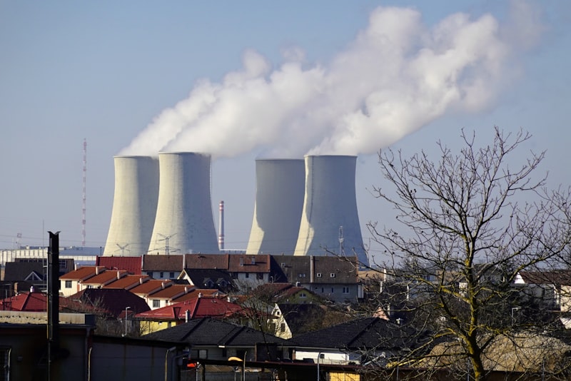 Four cooling towers emitting steam above a town