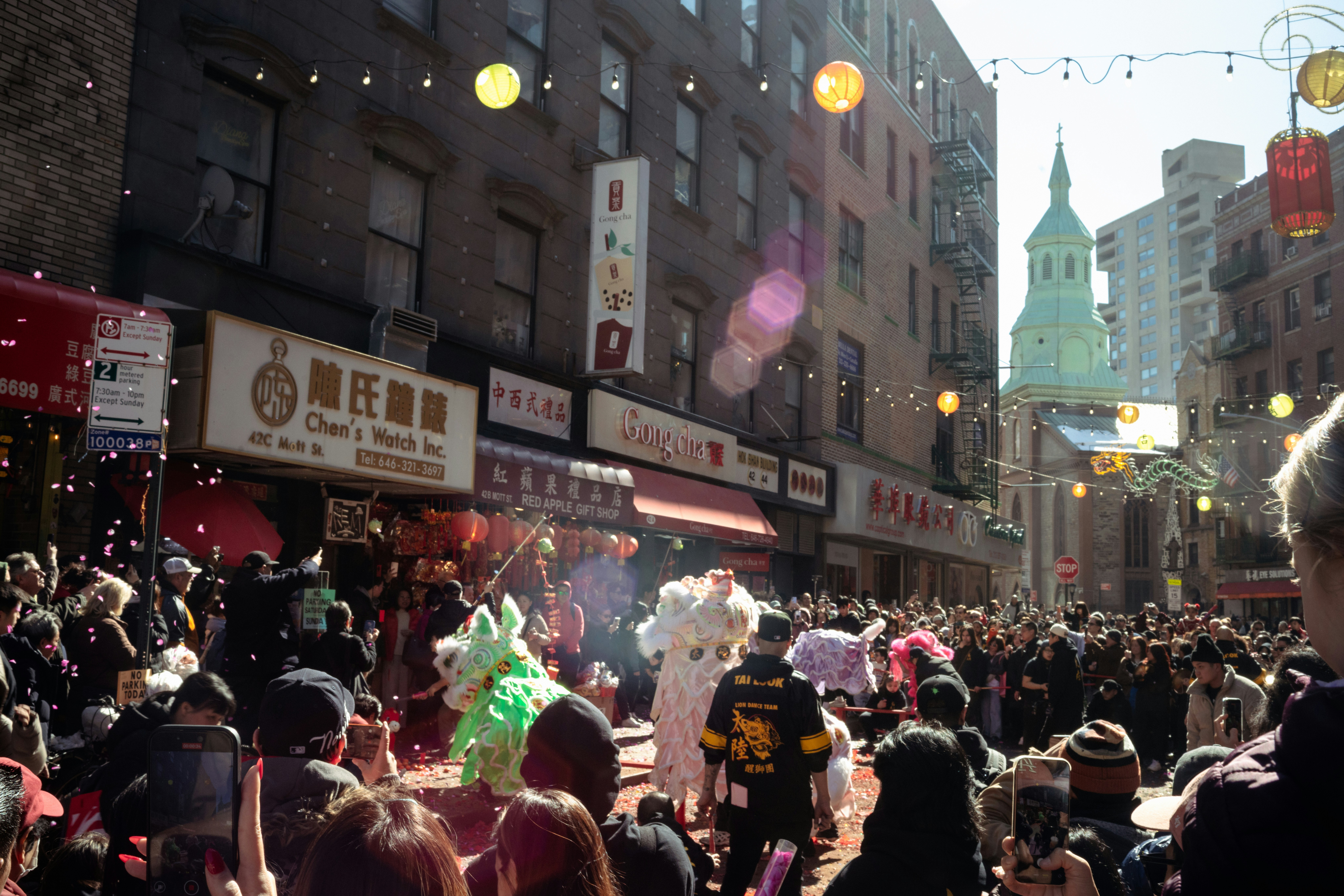 Crowds watch a dragon dance in a city street celebration.