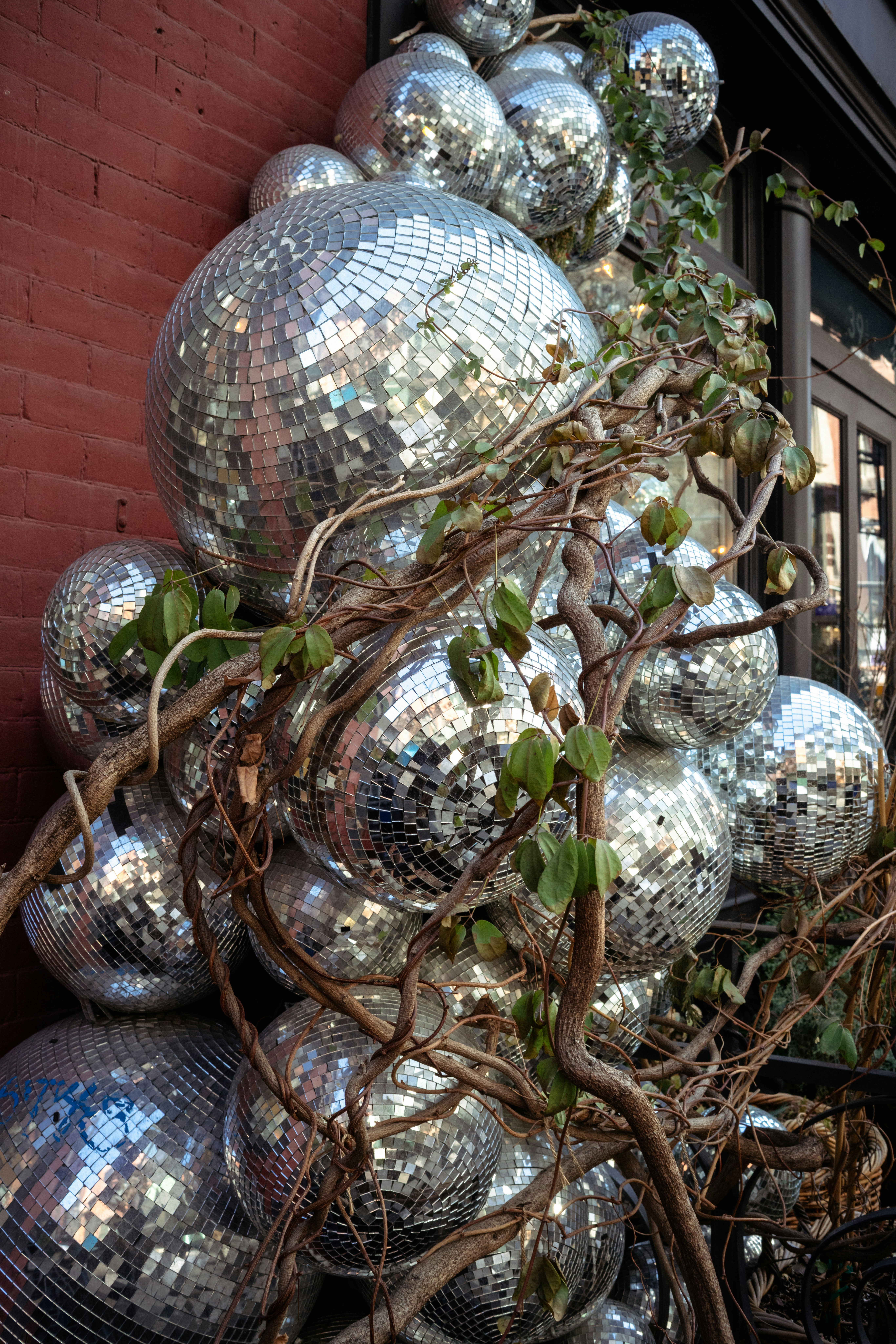 A pile of disco balls with vines growing around them.