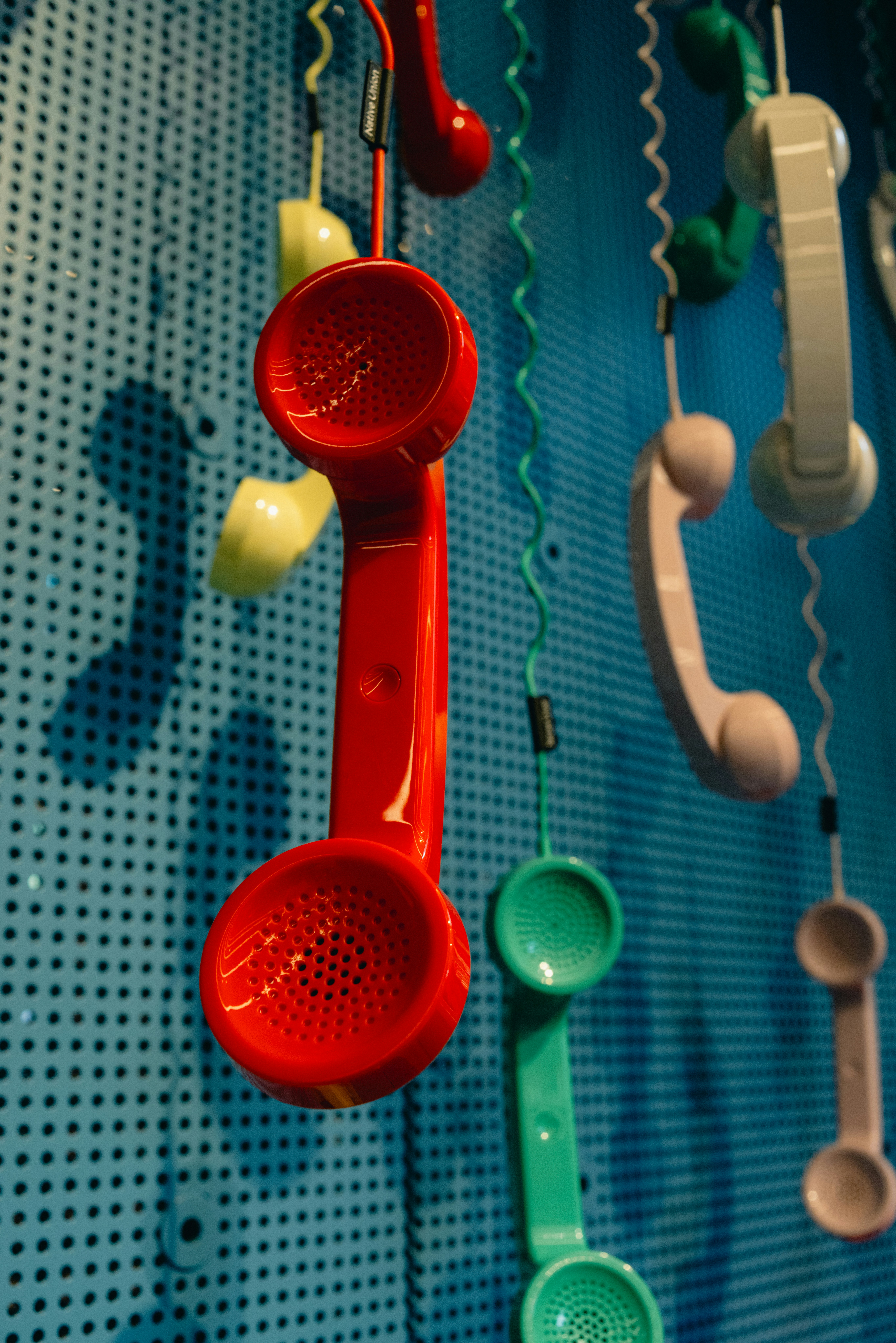 Colorful vintage telephone receivers hanging on a blue wall
