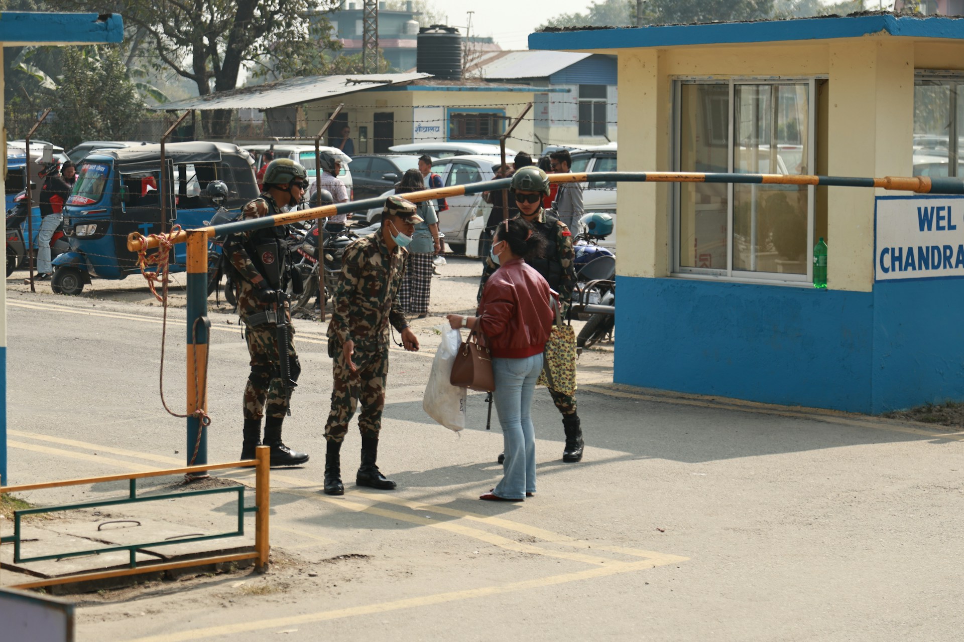 Soldiers check a woman at a checkpoint.