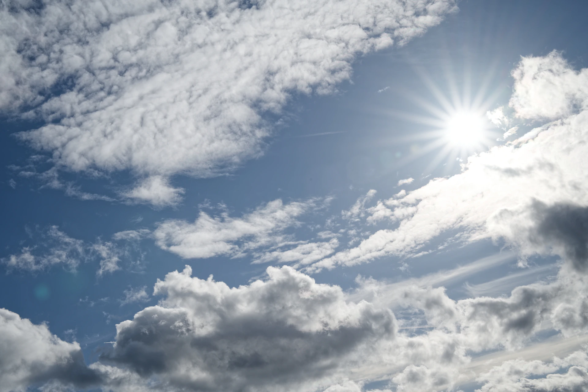 Bright sun shining through fluffy white clouds