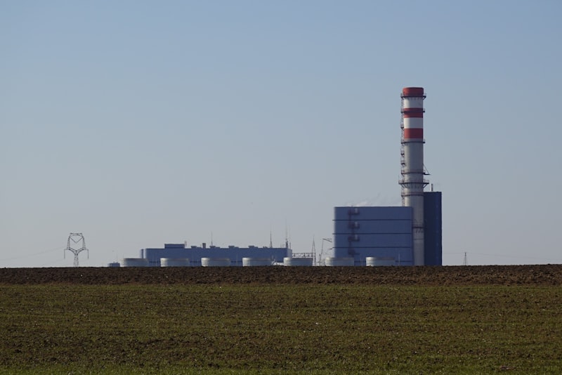 Industrial power plant with tall smokestack in distance