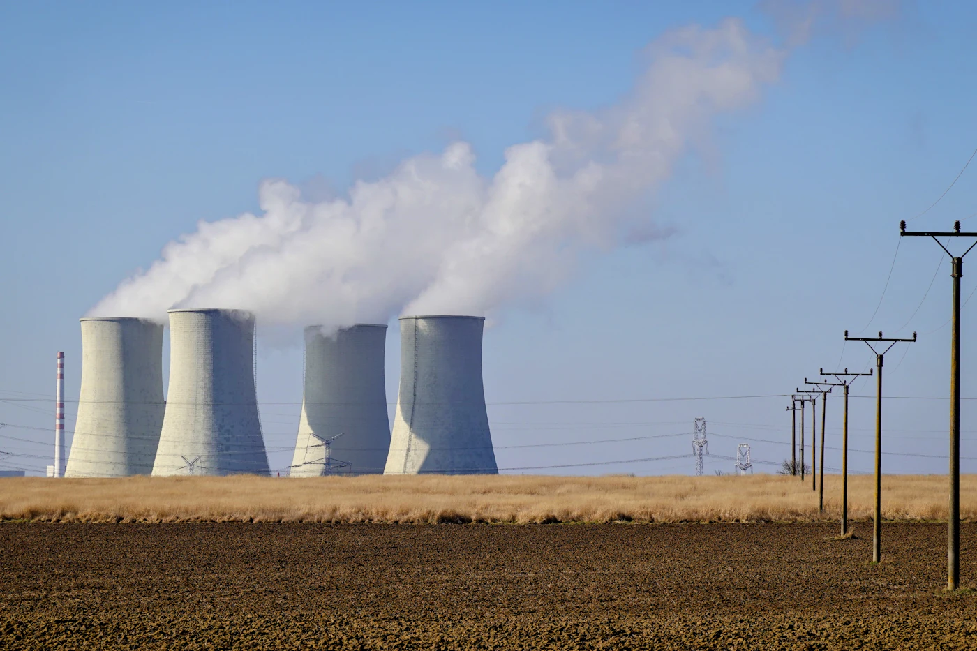 Power plant cooling towers releasing steam against a clear blue sky