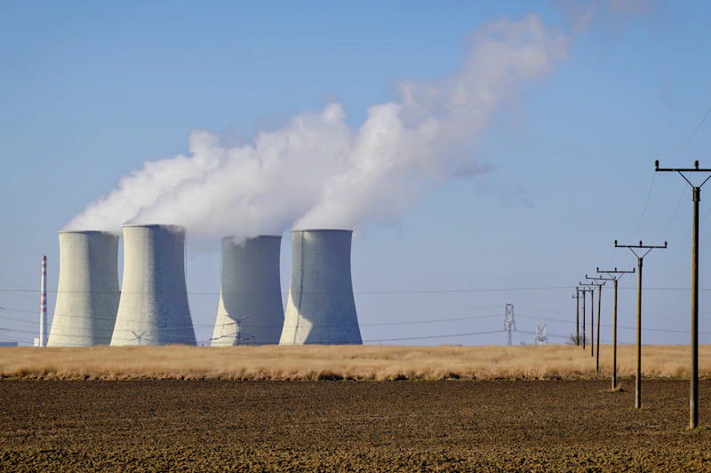 Cooling towers releasing steam against a clear blue sky