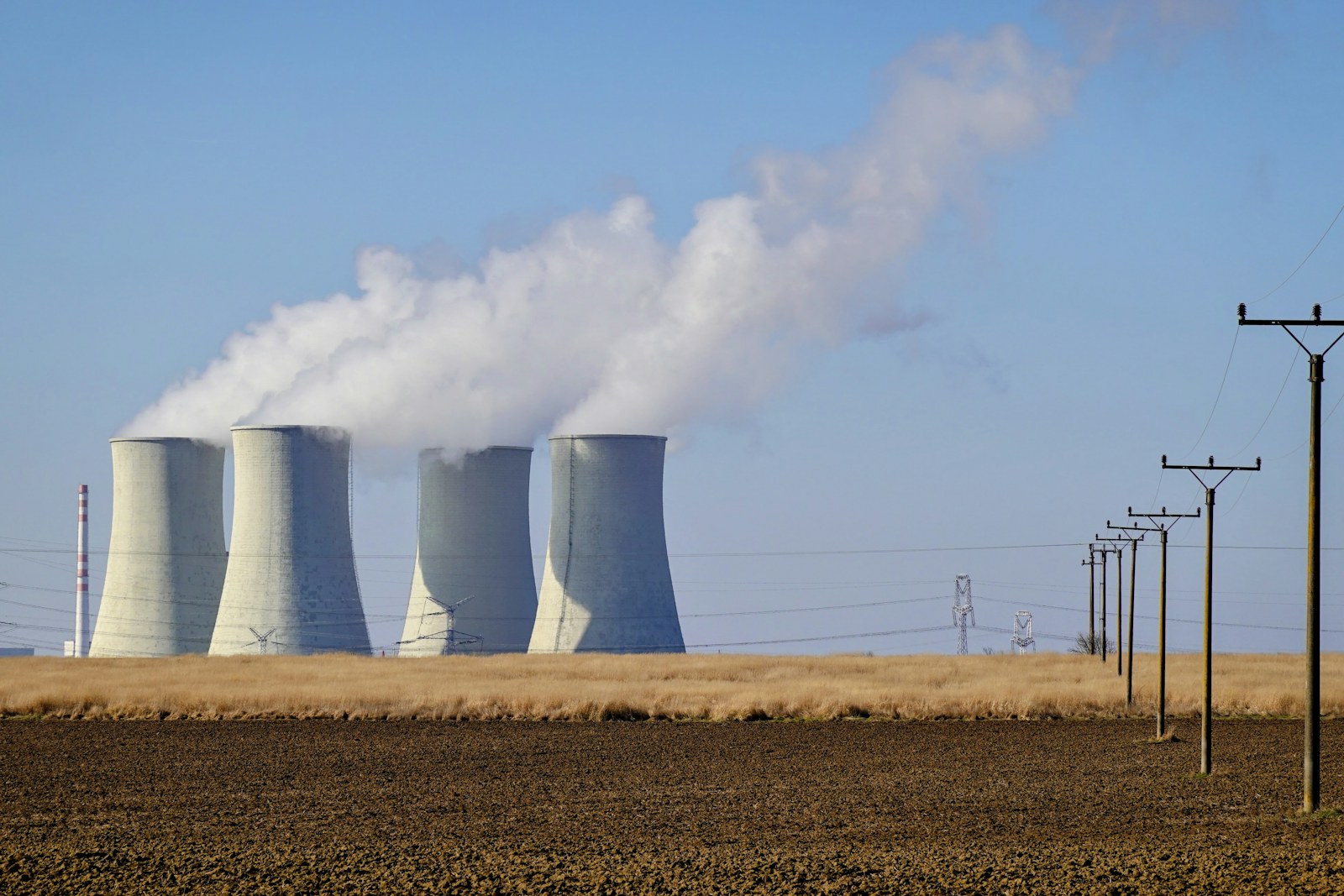 Cooling towers and power infrastructure under a clear blue sky
